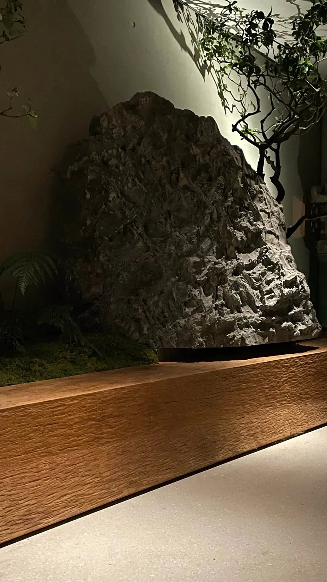 A dark room with a large grey rock in the foreground and a smaller grey rock in the background, set against a dramatic lighting effect