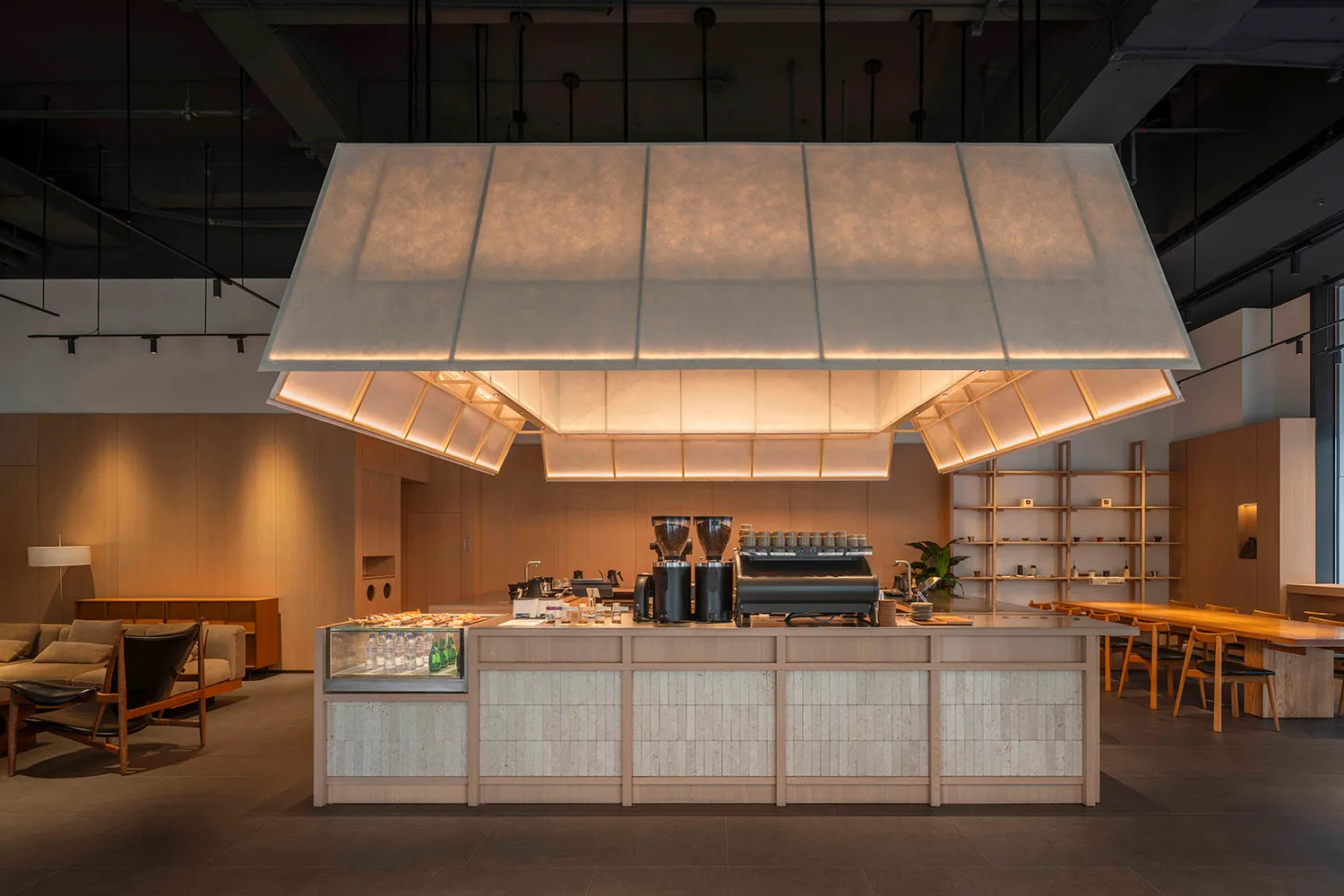 Warm and inviting cafe interior with a wooden counter, soft lighting, and a variety of cups and bottles on display