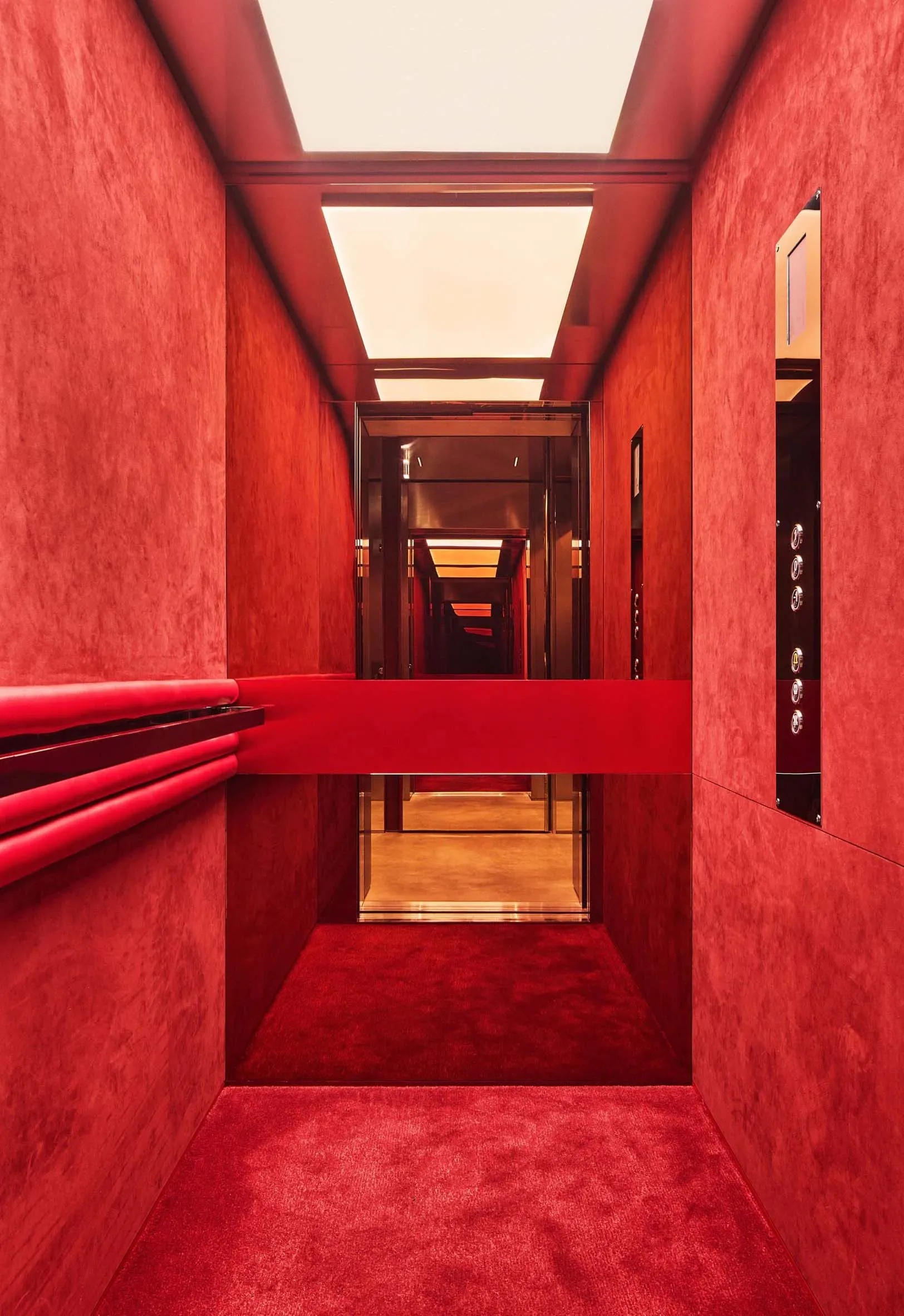 A narrow hallway with a red carpeted floor, dim lighting, and a warm red color scheme