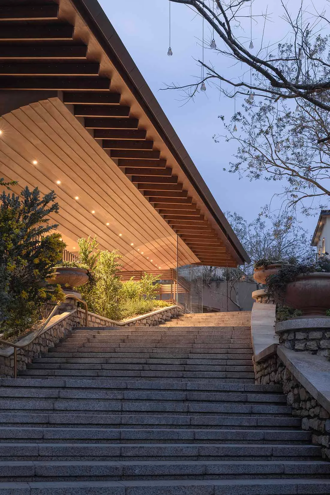 A modern building with a stone staircase leading up to a wooden door, set against a dimly lit background