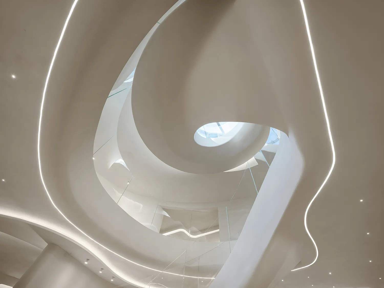 A minimalist museum with a spiral staircase made of concrete and glass railing, bathed in natural light from a window