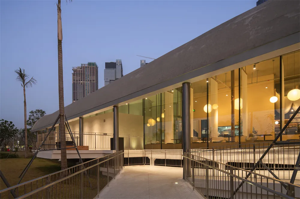 A dimly lit lobby with a large glass wall, showcasing a modern architectural style with clean lines and minimalistic design