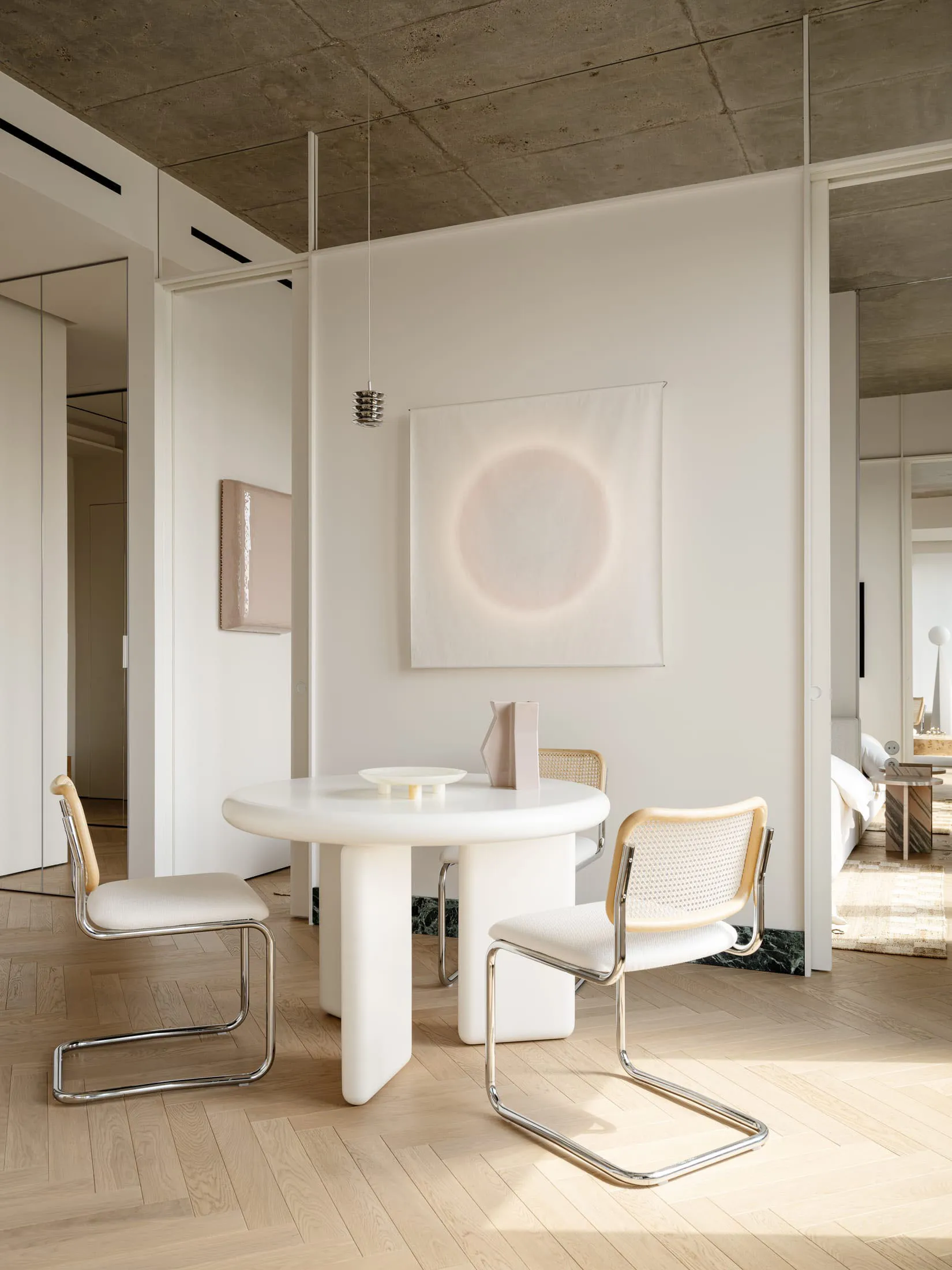 Cozy modern living space with a white color scheme, a dining table, a bed, and soft warm lighting