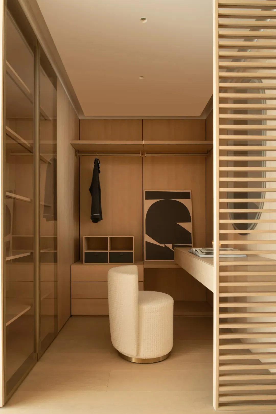 A cozy study with wooden walls and floors, featuring a desk, chair, closet, and mirror, with a laptop and book on the desk