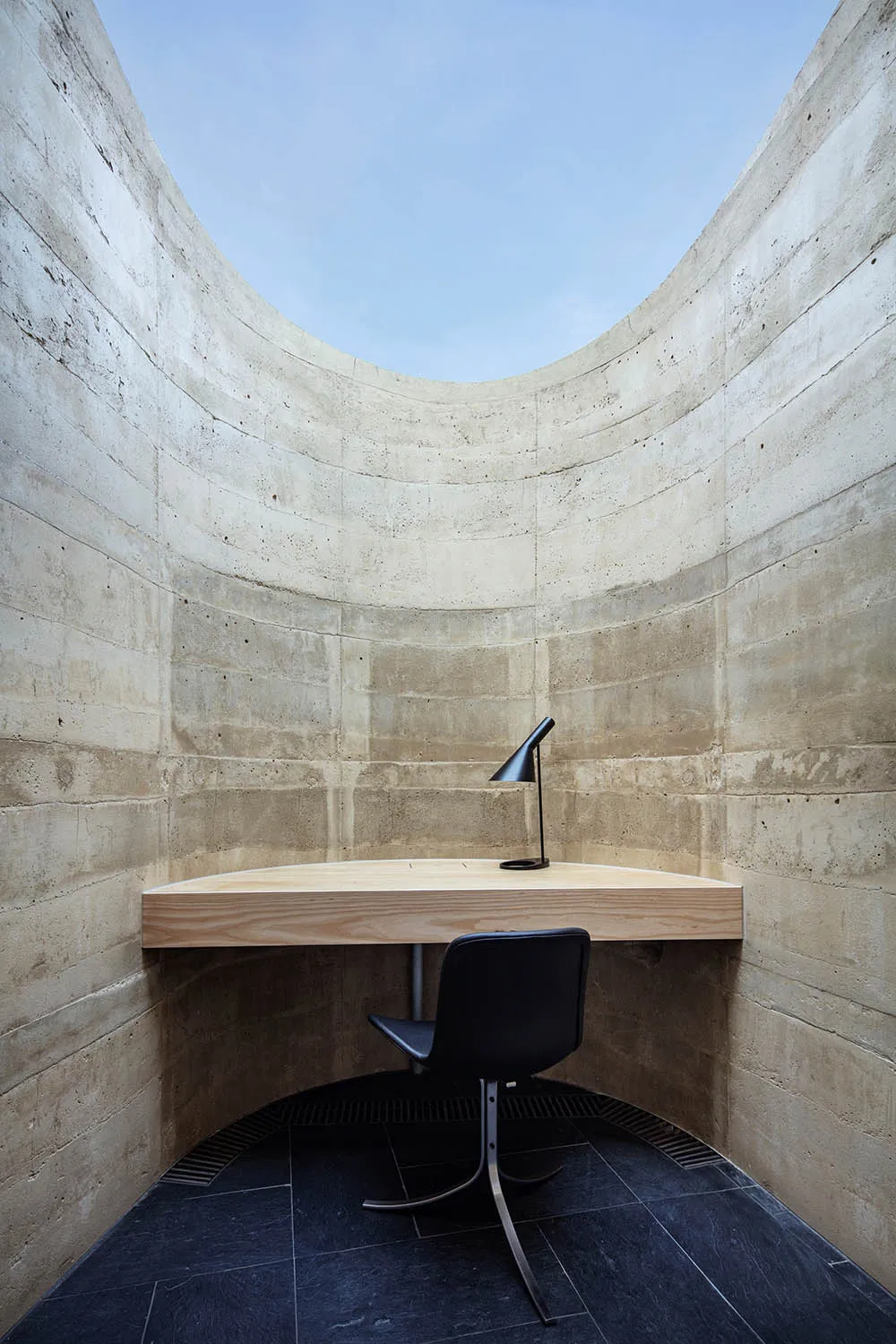 Small office space with a wooden desk and chair, wooden floor, and a window in the background