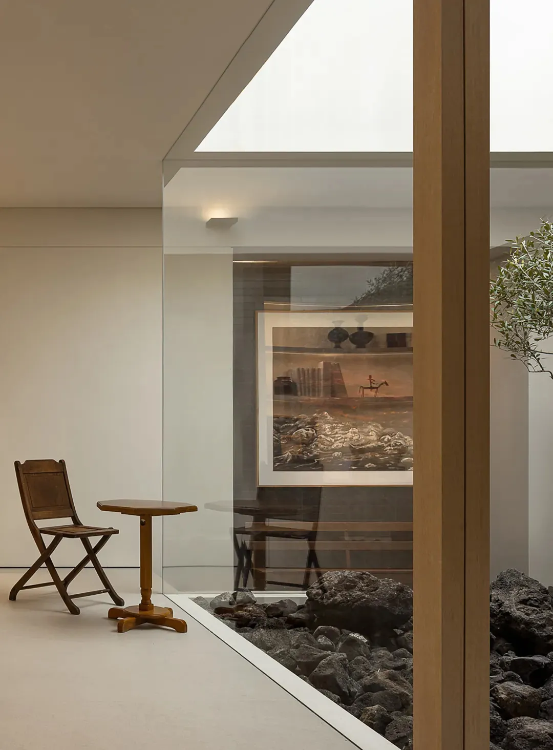 A modern living room with a glass wall, natural light, wooden furniture, and a potted plant, creating a bright and inviting atmosphere