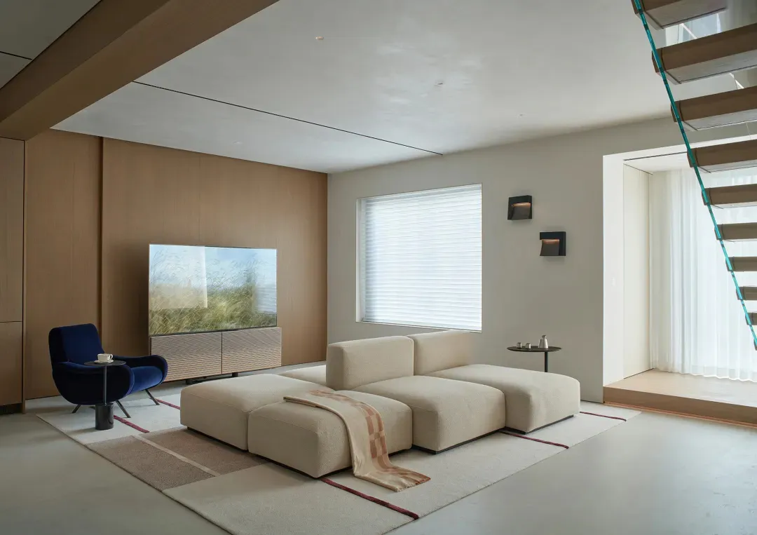 A well-lit living room with a large couch, flat screen TV, rug, chair, and two lamps, creating a comfortable and inviting atmosphere