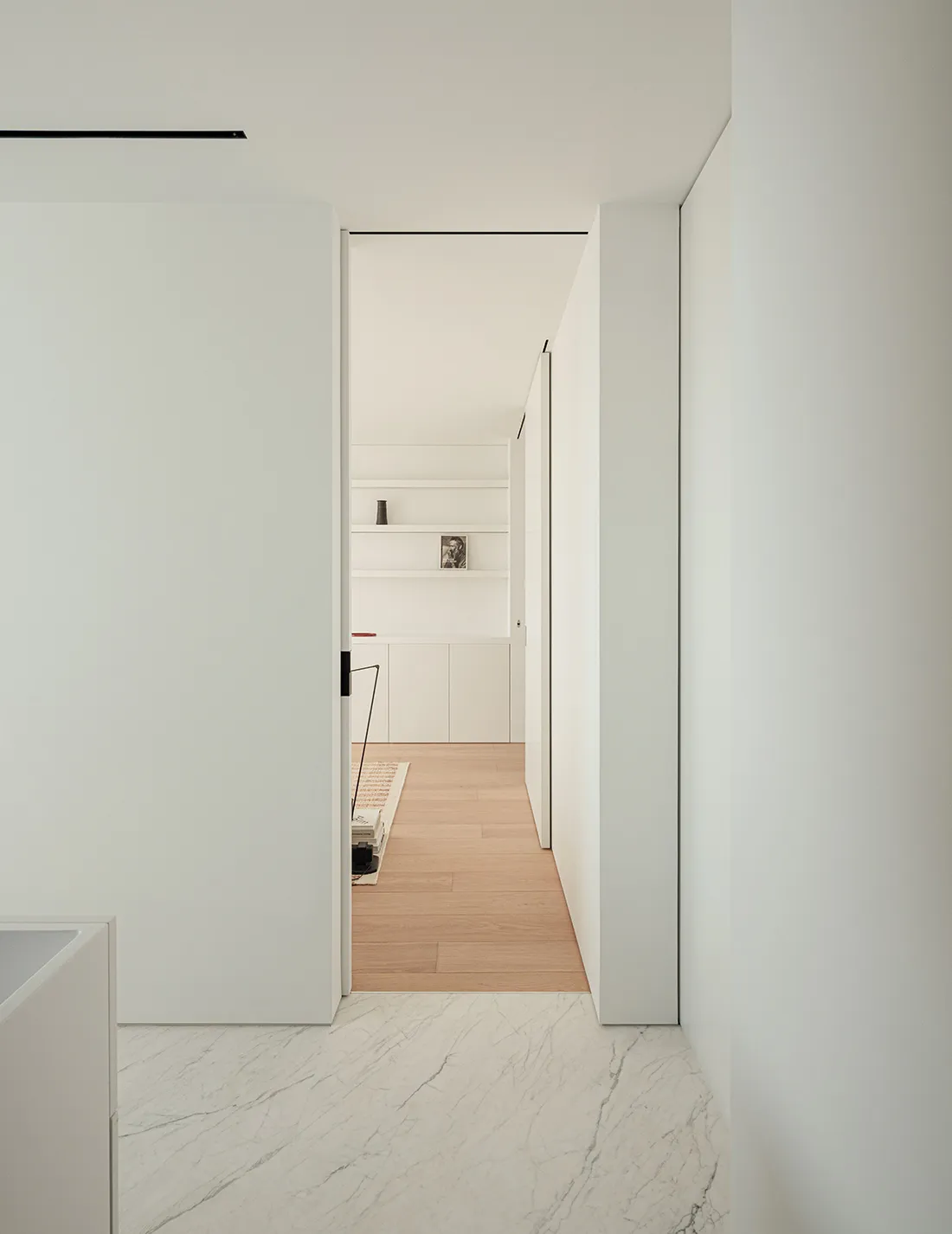 A bright and inviting kitchen with a wooden floor, a white door, and a refrigerator visible through the open door