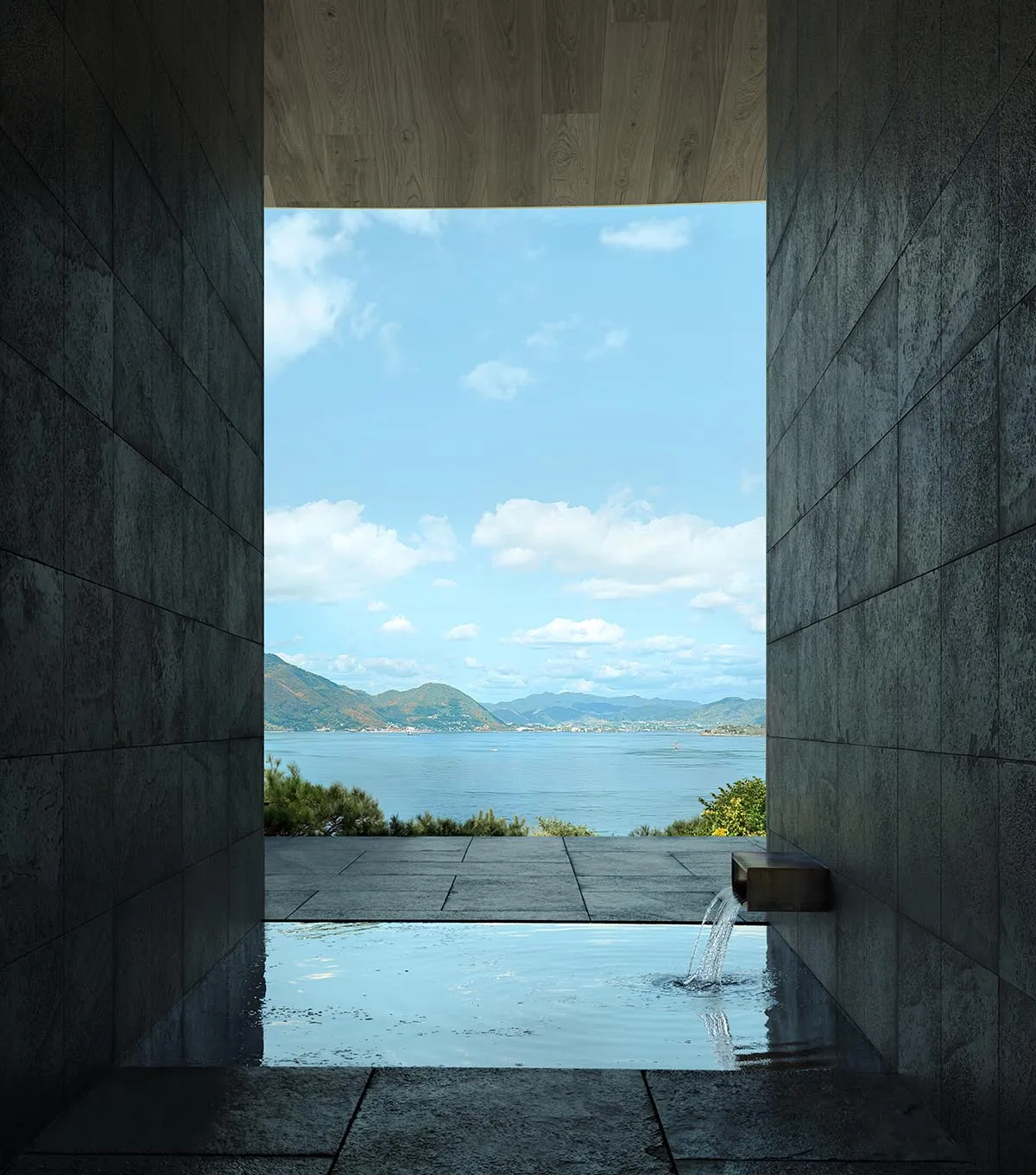 A serene spa or bathroom with a large pool, stone walls, and a stunning ocean view through a large window