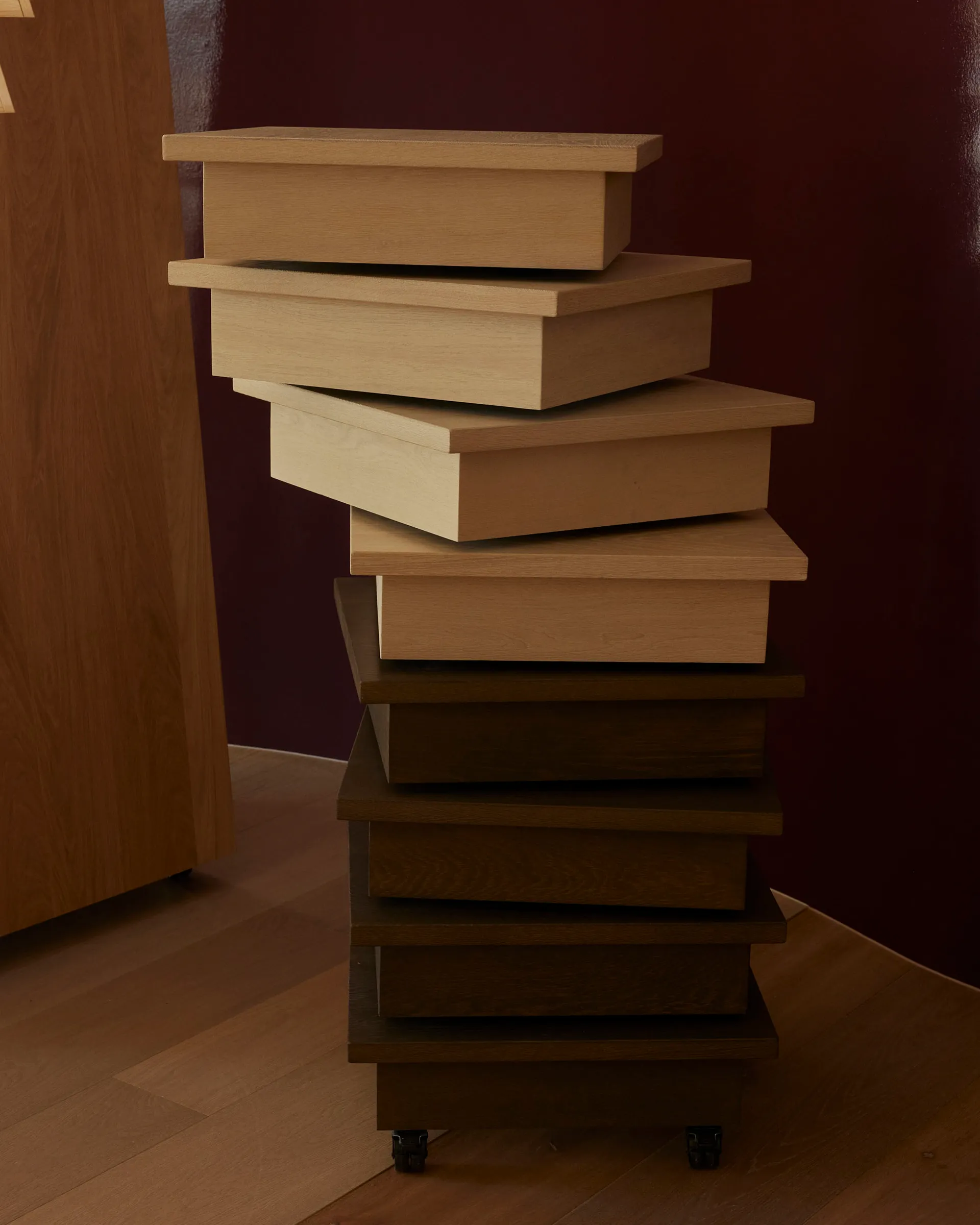 A pile of wooden boxes in a room with a wooden floor, lit by natural light