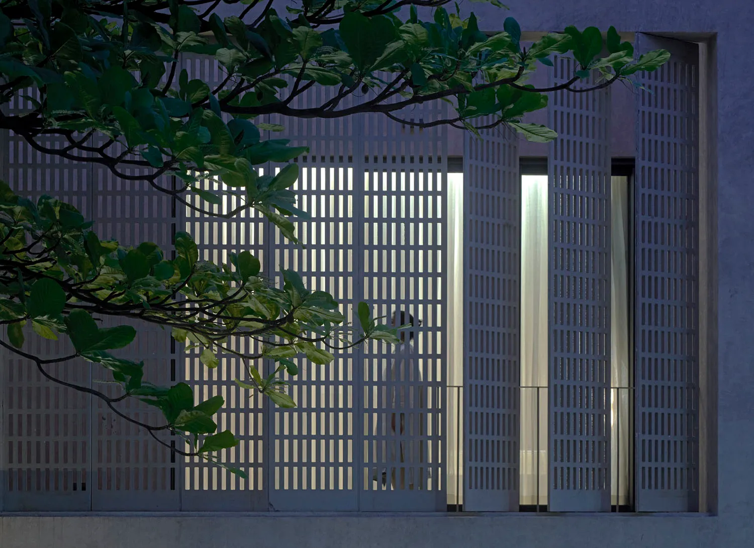 A white dog stands in a window of a modern building, looking out at the scene outside