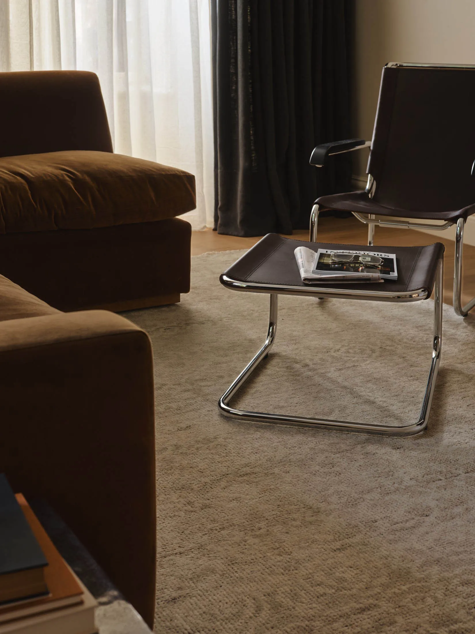 A modern living room with a brown couch, chair, and coffee table, set against a carpeted floor with a magazine on the coffee table