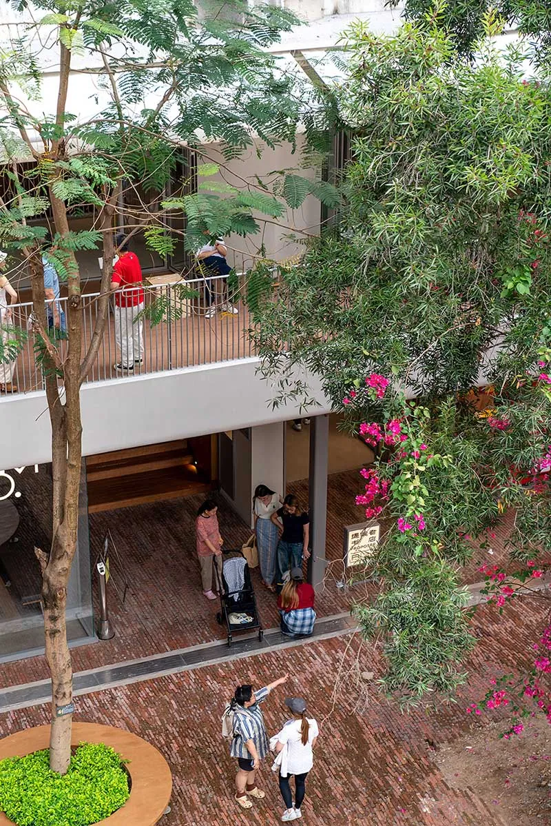 A lively retail space with a brick floor, filled with people shopping and socializing, under bright lighting