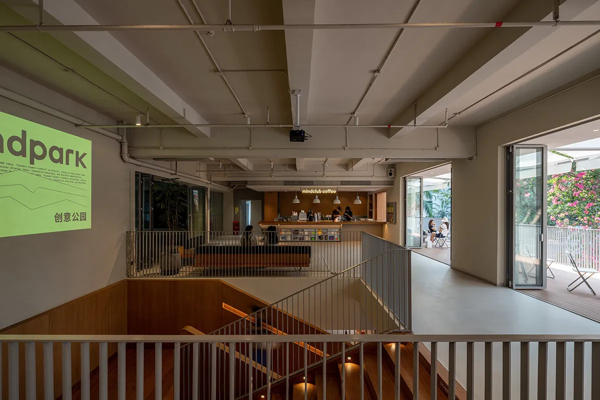 A large, open space with a staircase, balcony, and comfortable seating areas, featuring wood and metal materials and well-distributed lighting