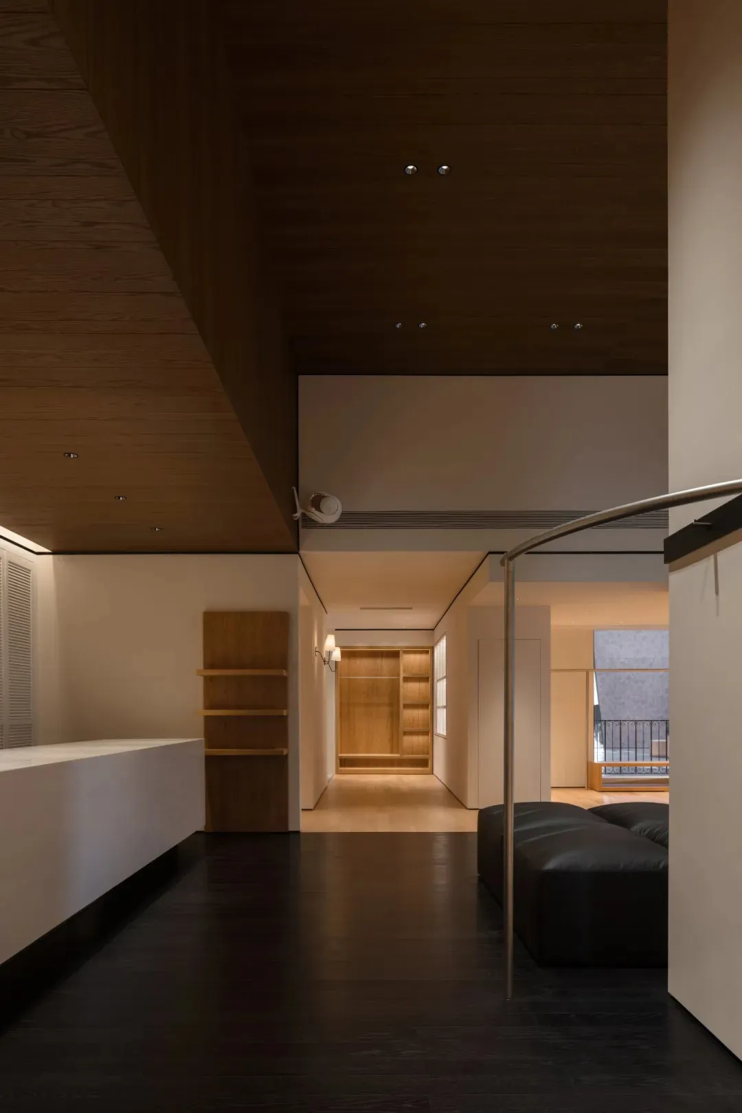 Open living space with a black couch, wooden elements, and a kitchen counter, featuring a warm and cozy atmosphere with dim lighting