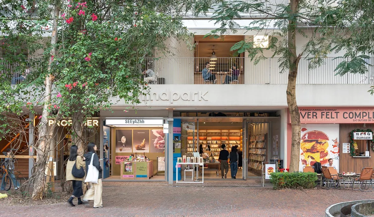 A modern bookstore with a brick floor, wooden furniture, and natural light from windows, creating a warm and inviting atmosphere for customers to browse and read