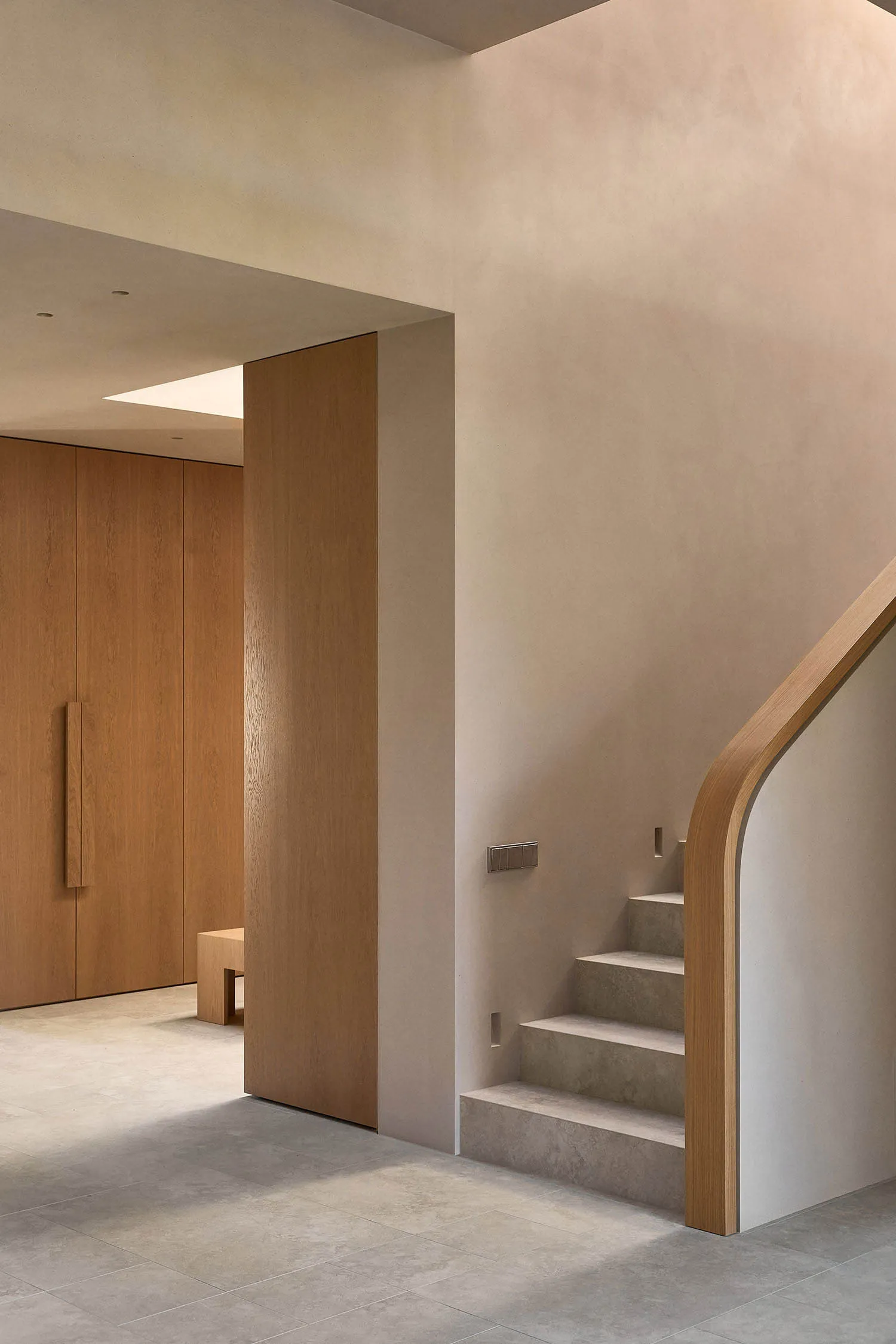 A wooden staircase in a cozy home with a white color, located in a hallway with a doorway at the bottom of the stairs