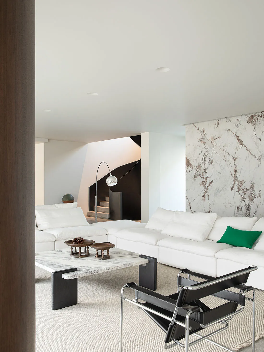 Comfortable living space with a white couch, chair, and coffee table, featuring a large window and natural light, decorated with a vase and bowl