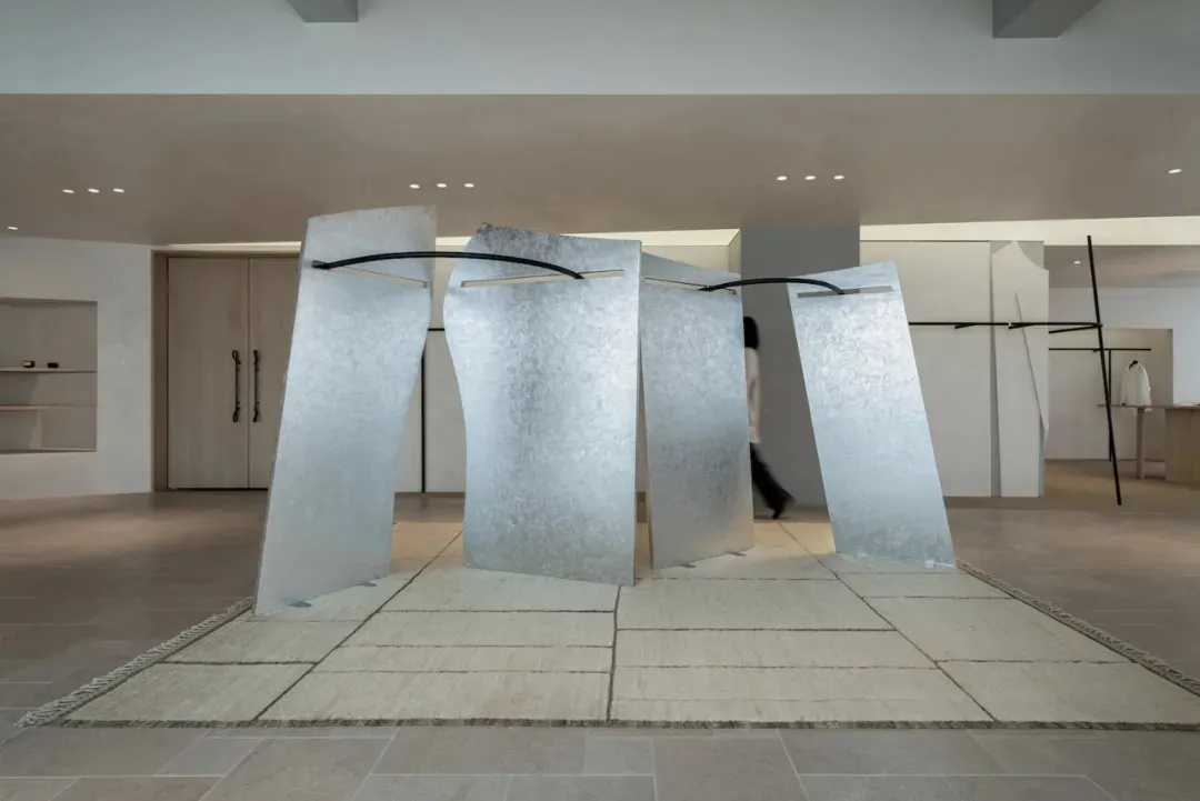 A contemporary gallery space with a large metal sculpture as the main attraction, surrounded by soft and diffused lighting
