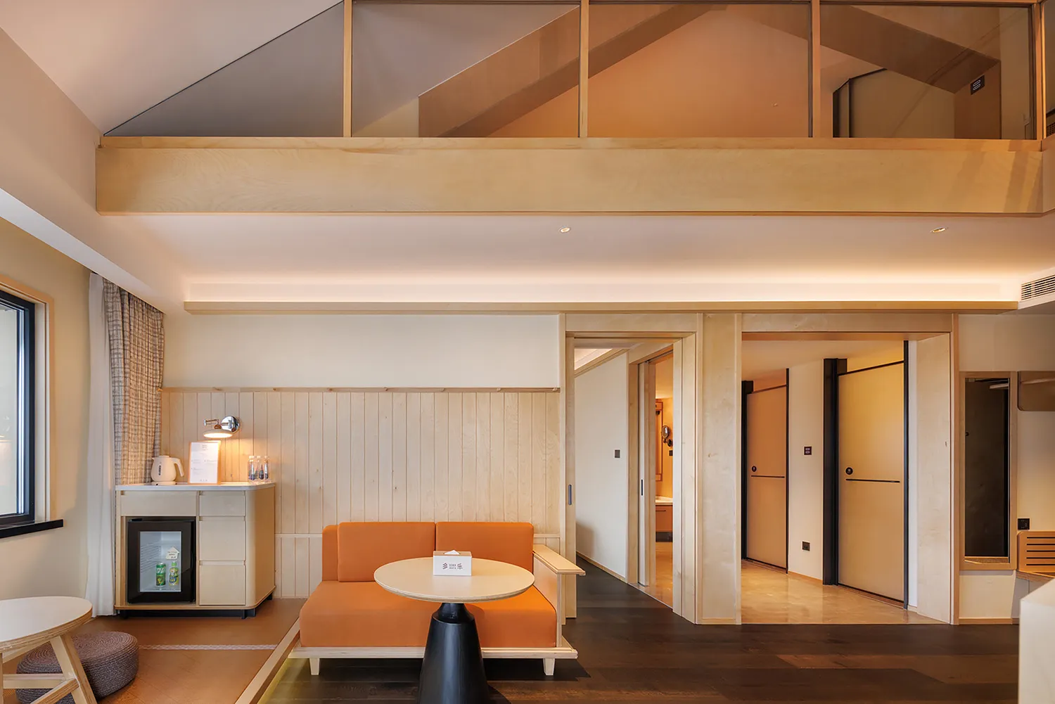 A warm and inviting living room with a wooden floor and walls, featuring a couch, dining table, and chair arranged in a comfortable manner