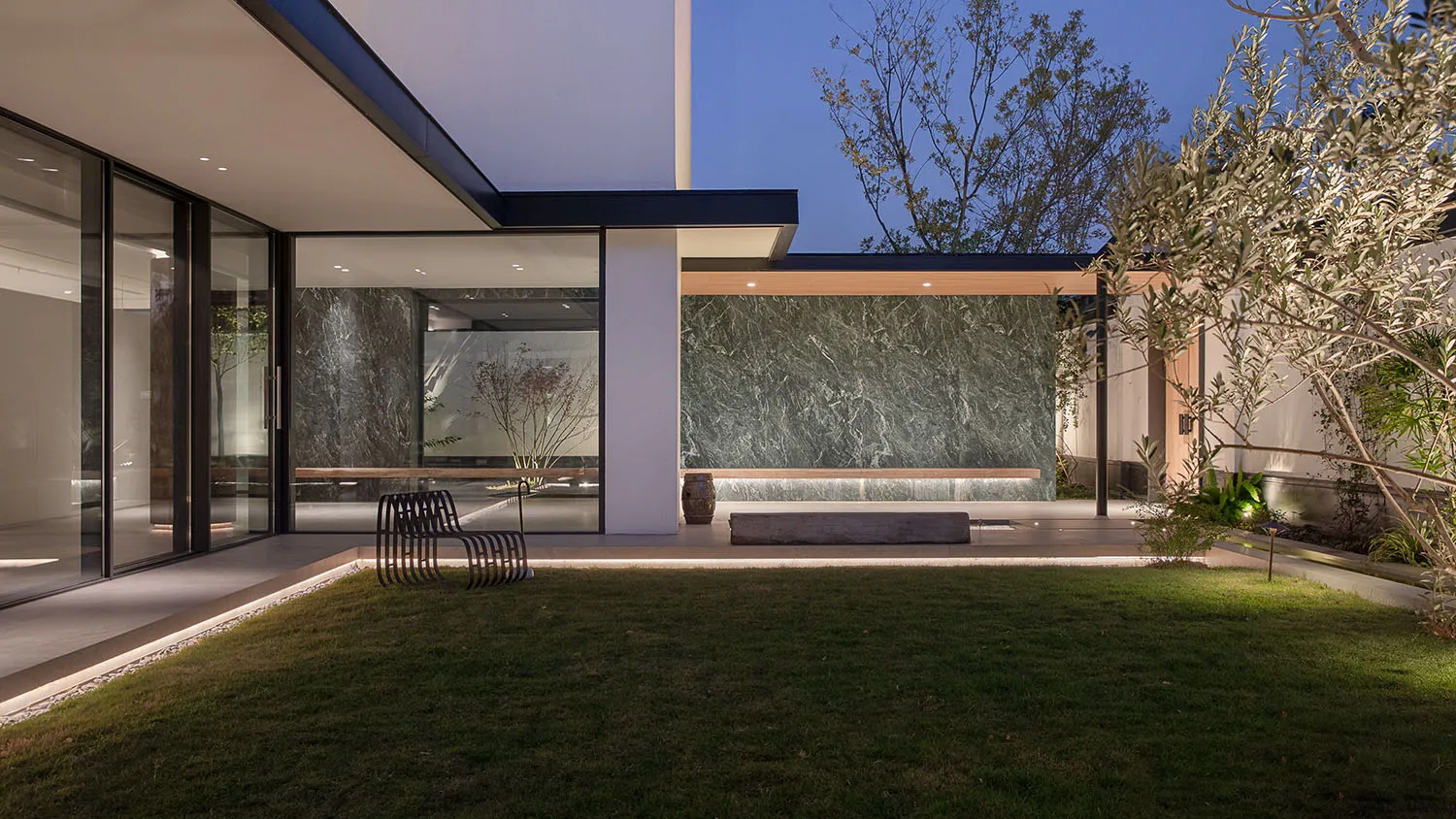 A well-lit, modern house with a white exterior, black roof, and a luxurious marble wall inside, with natural light pouring in through a large window