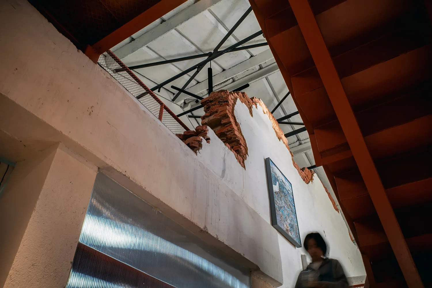 A woman walks up a staircase in front of a partially constructed building with a brick wall and a crane in the background, under natural light