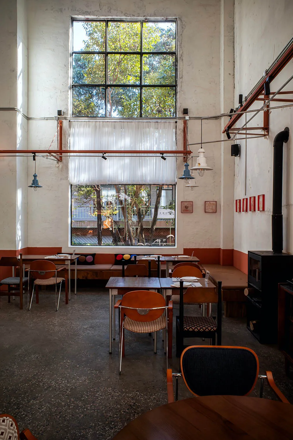 一間溫馨餐廳，擁有大片窗戶、木質家具與餐桌，自然光線與暖陽照耀