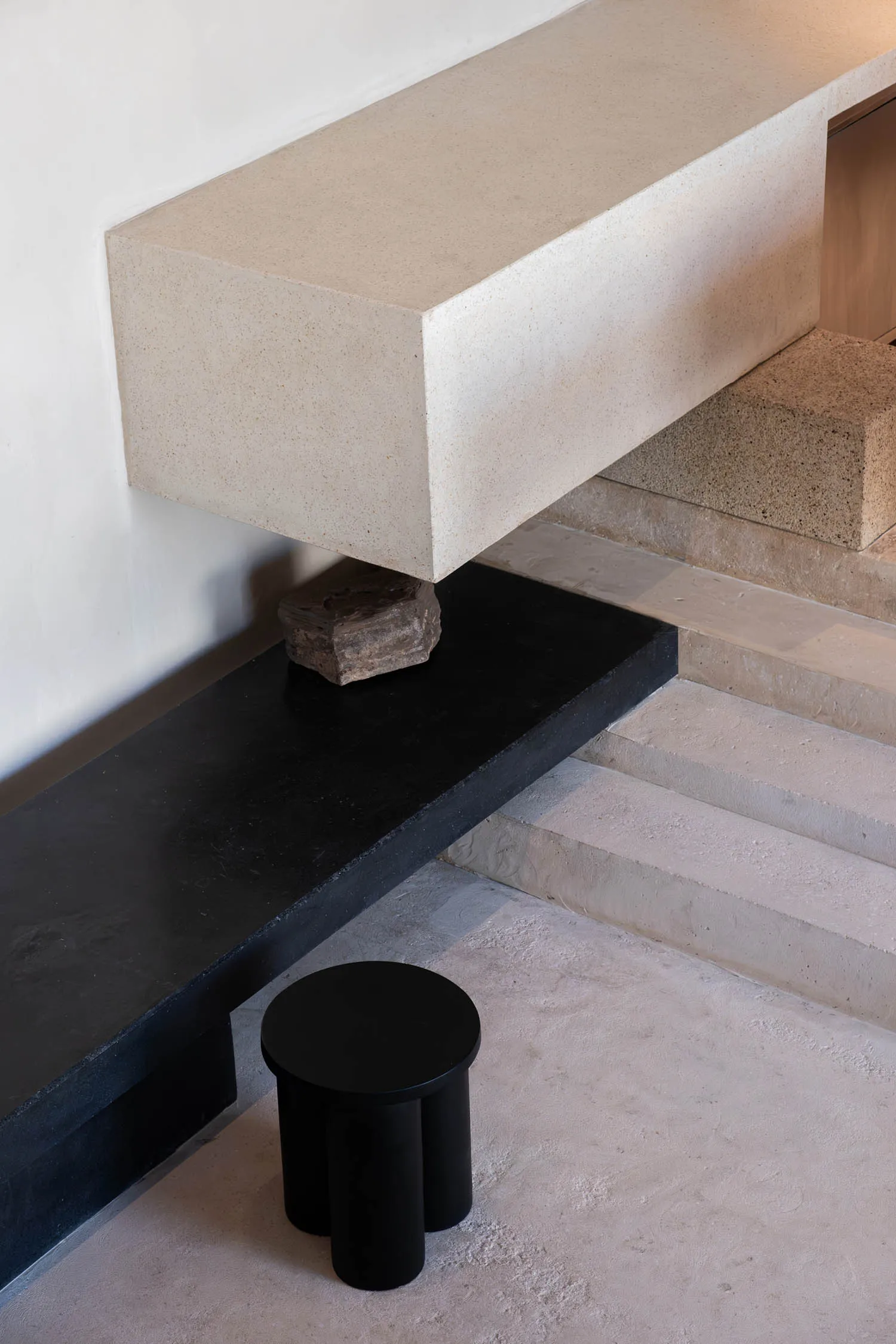 昏暗燈光的樓梯，底部階梯上有一張黑色長椅，周圍環繞石階