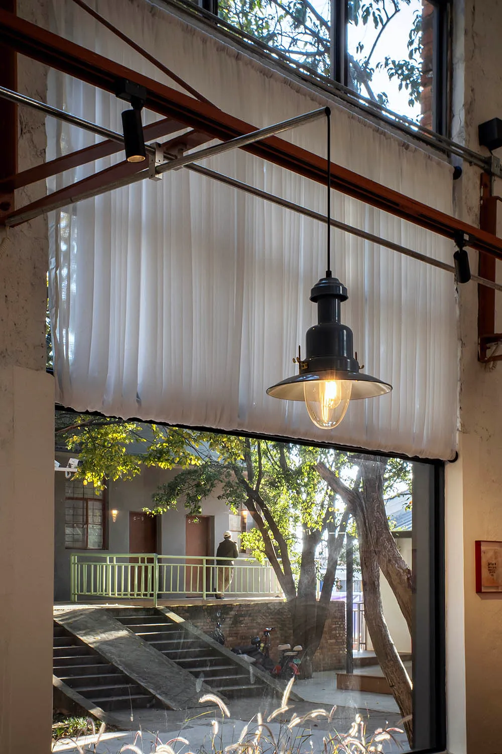 A bright and welcoming living space with a dining table, chairs, couch, and chair, featuring a large window, balcony, and tree outside