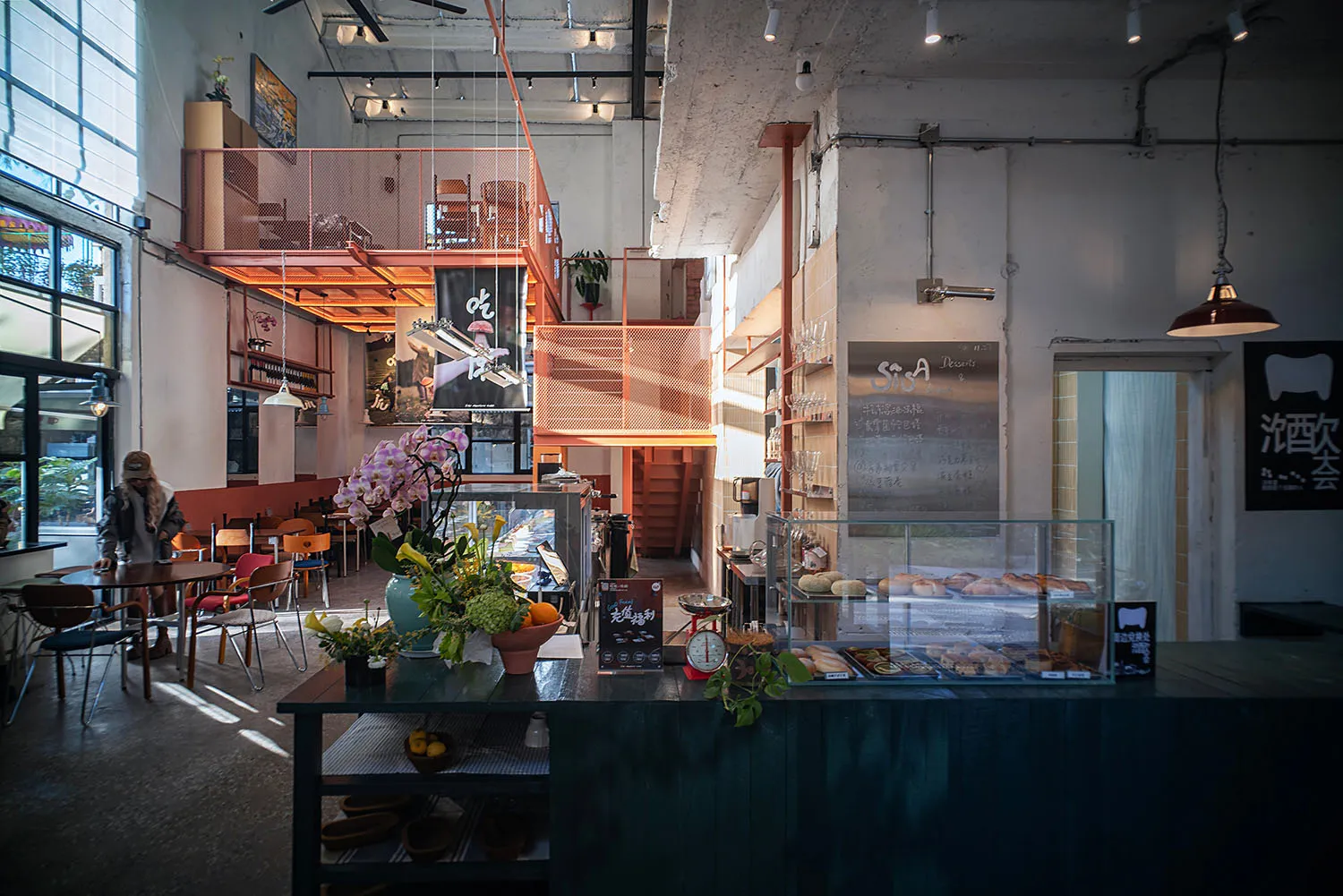 A modern restaurant with a large open dining area featuring a counter, dining table, and chairs, with a mix of natural and artificial lighting creating a warm and inviting atmosphere