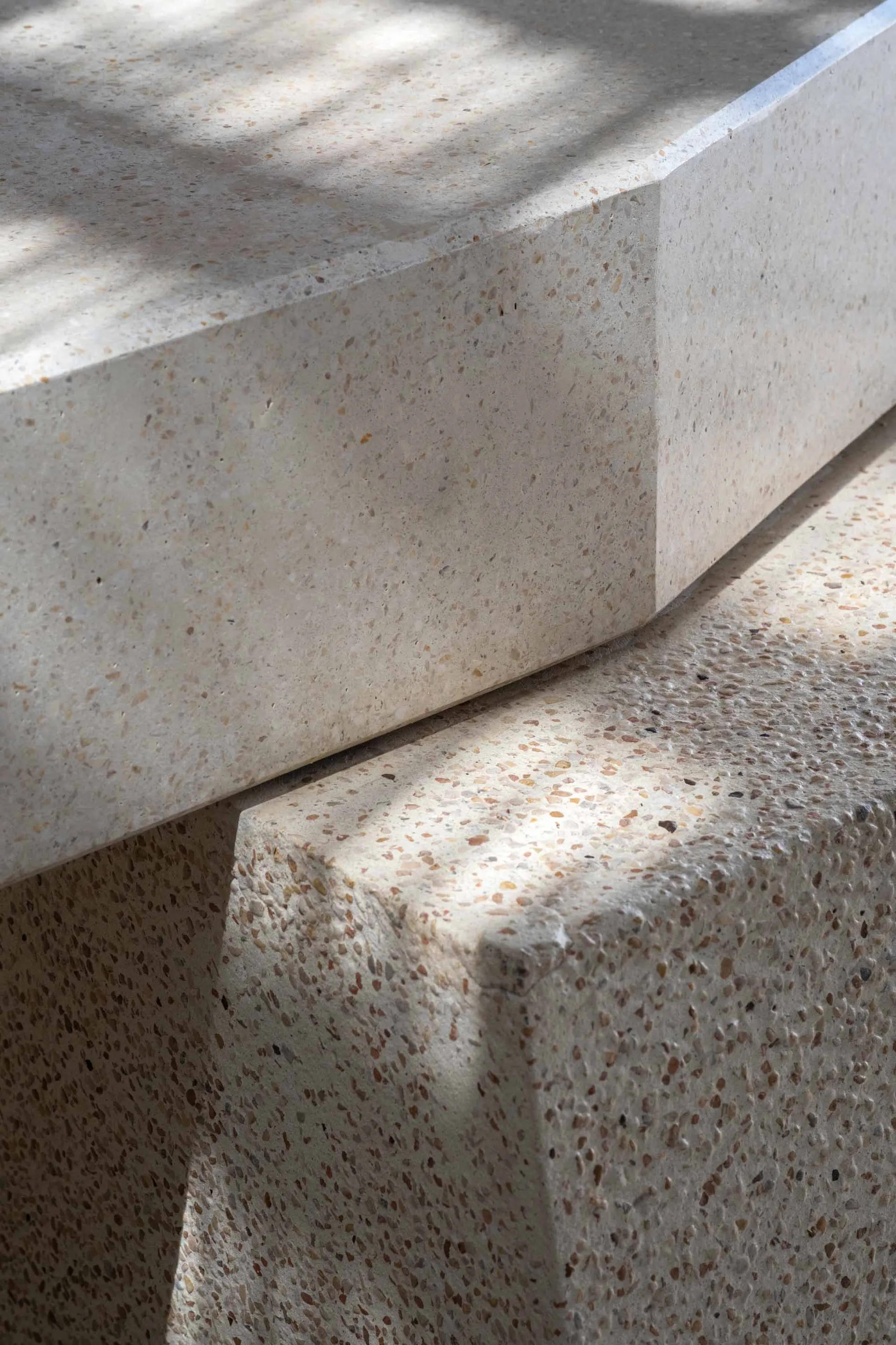A close-up photograph of a textured surface with a combination of concrete and wood, featuring a shadow cast on it, creating a calm and serene atmosphere
