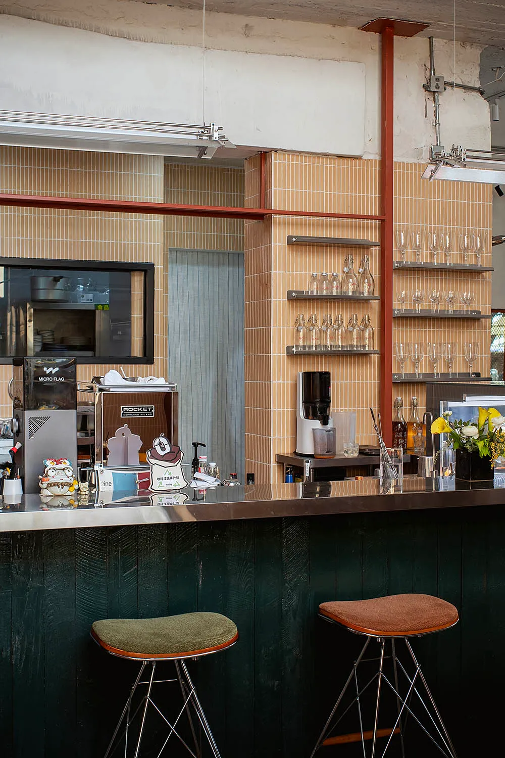 Cozy modern bar with a wooden counter, tile backsplash, and brown stools, featuring various items on display