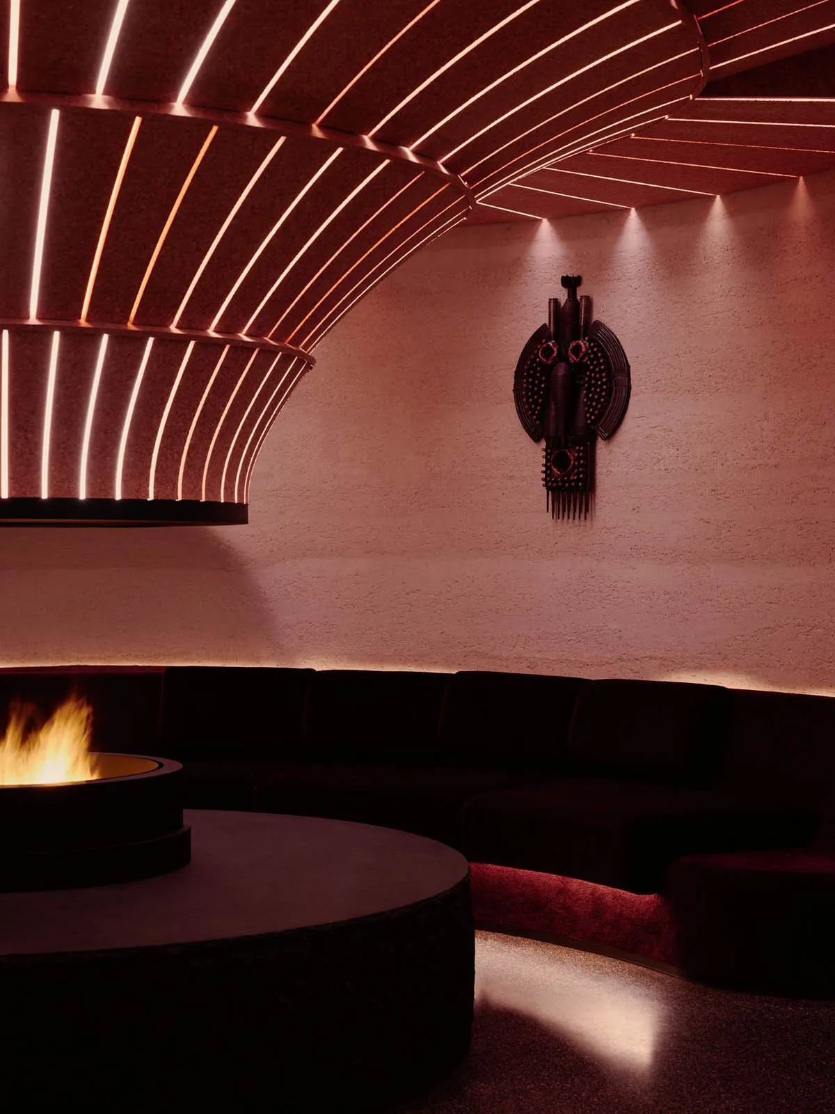 Cozy living room with a black couch, chair, and fireplace, illuminated by a fire