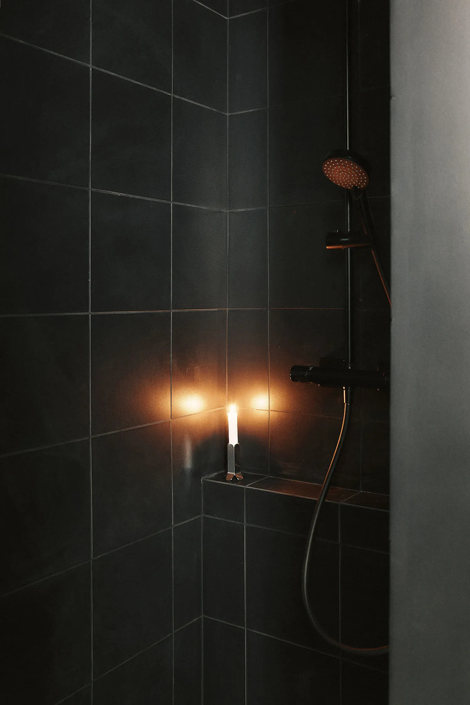 A modern bathroom with a glass shower, toilet, and sink, featuring tiled walls and dim lighting