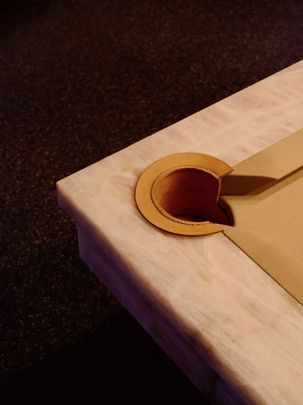 A dimly lit room with a wooden table and a brown leather item on it, set against a carpeted floor