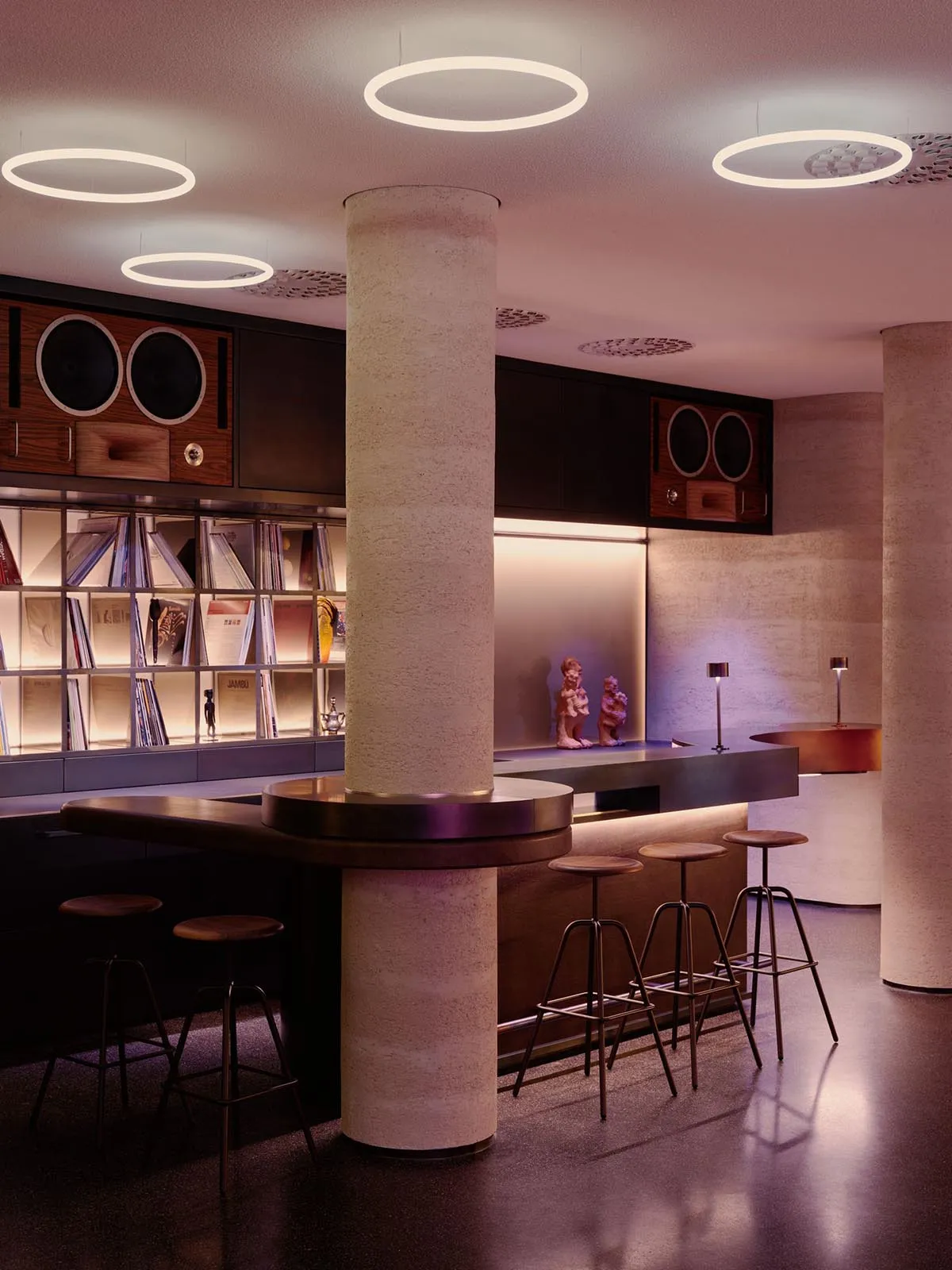 A modern bar with a wooden counter, sink, and stools, surrounded by stylish decor and well-lit with a mix of natural and artificial light