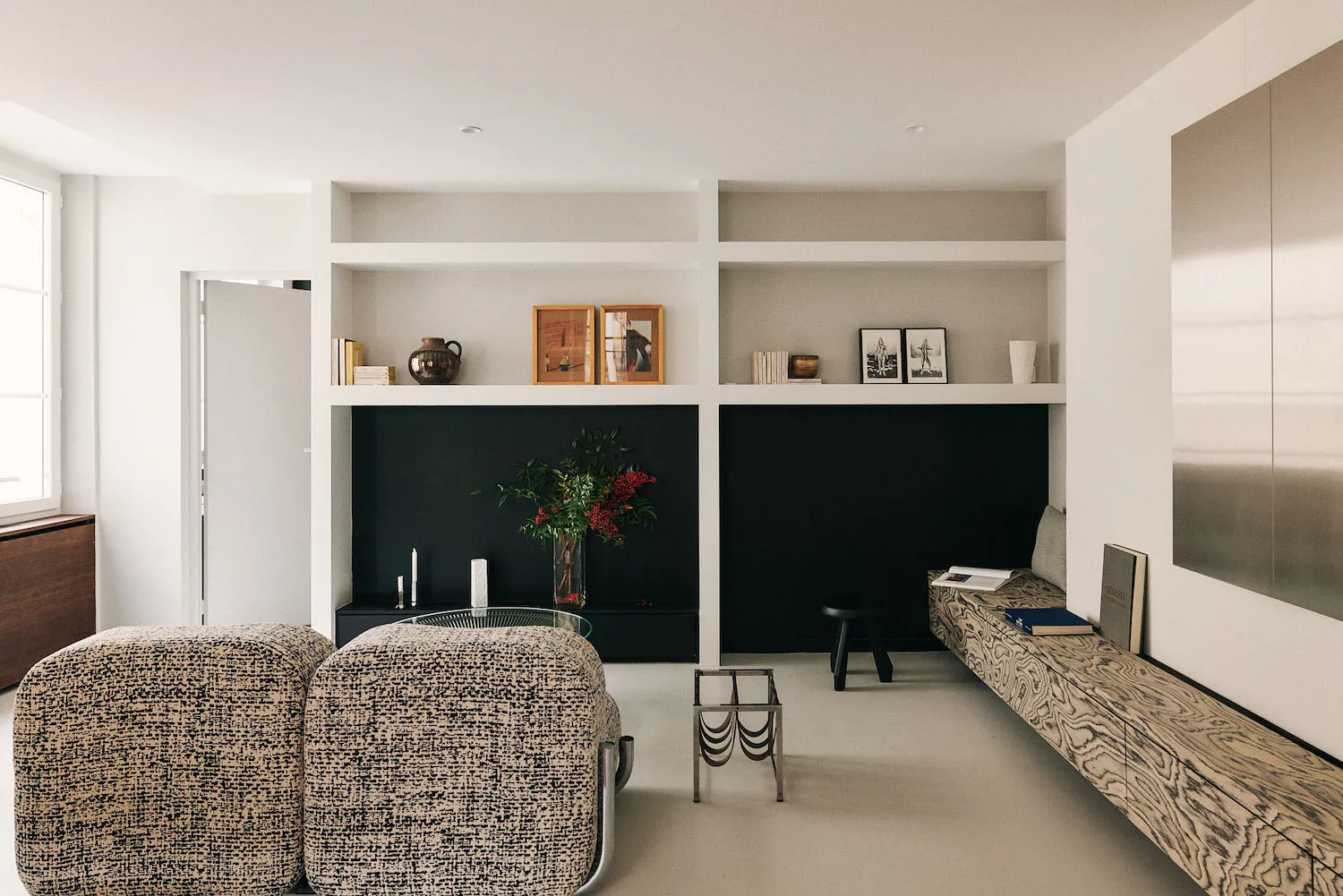 Cozy modern living space with a black and white color scheme, featuring a couch, chair, coffee table, and bookshelf with books, and a vase with flowers adding a pop of color