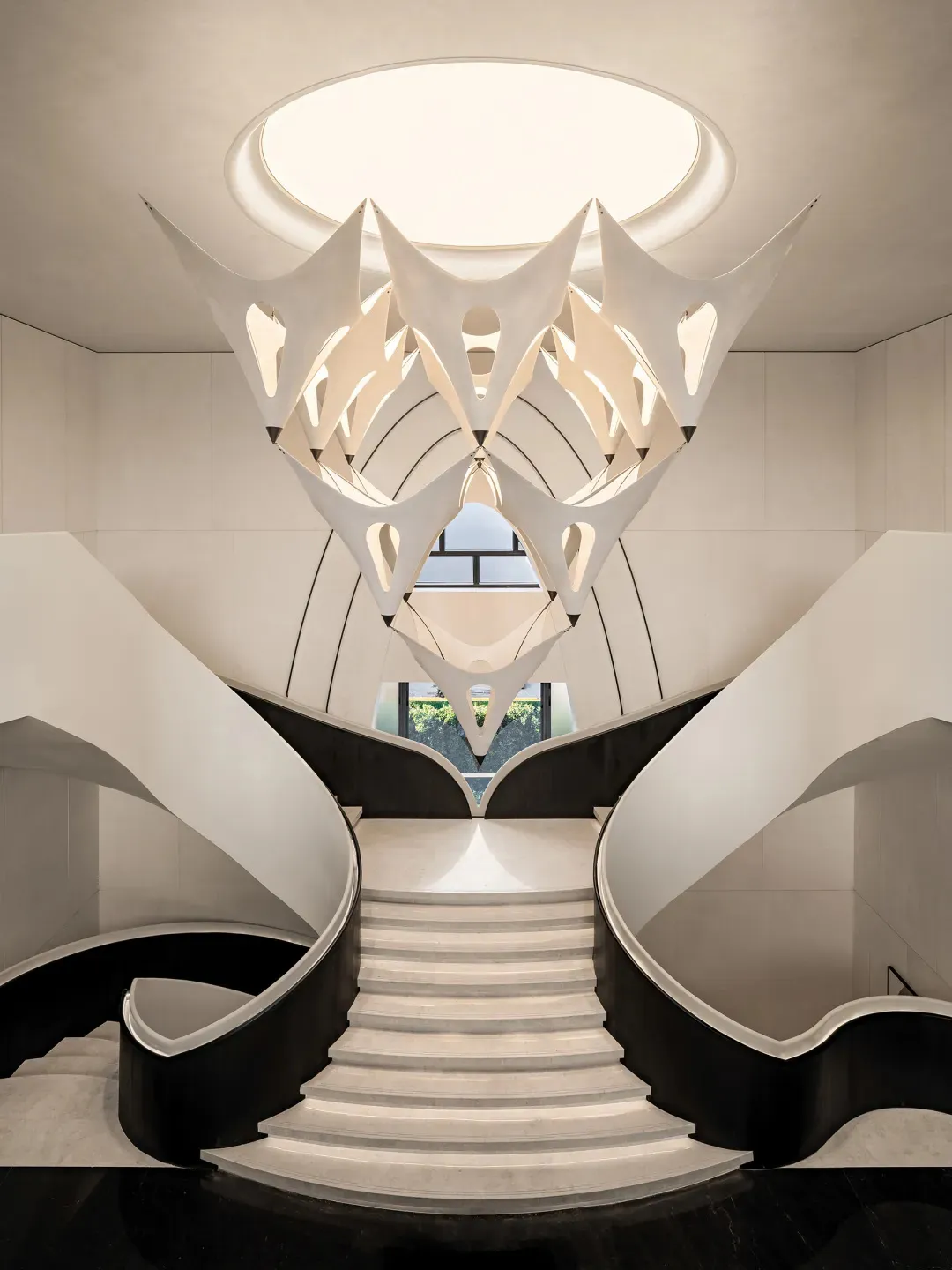 A modern staircase with a white railing and white stone wall, bathed in natural sunlight