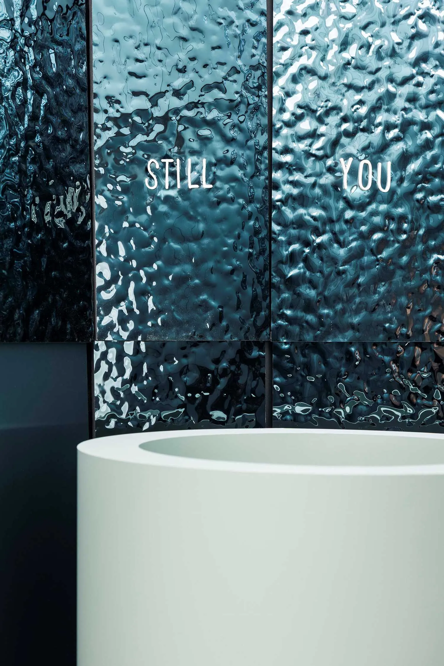 A modern bathroom with a white sink and a prominent blue wall, well-lit and clean