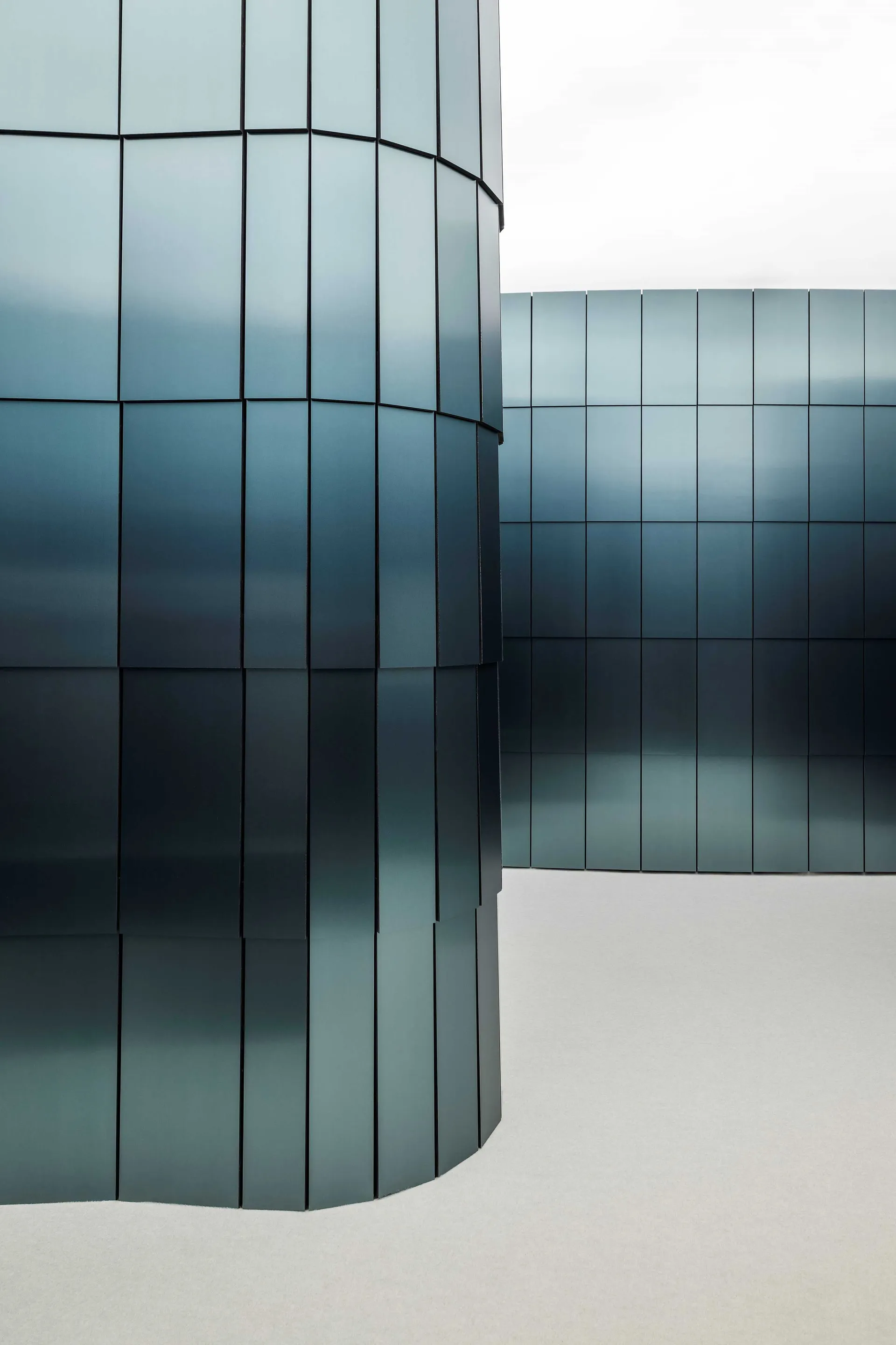 A modern building with a glass exterior, featuring a large glass wall that reflects the surrounding environment, in a contemporary and minimalist style