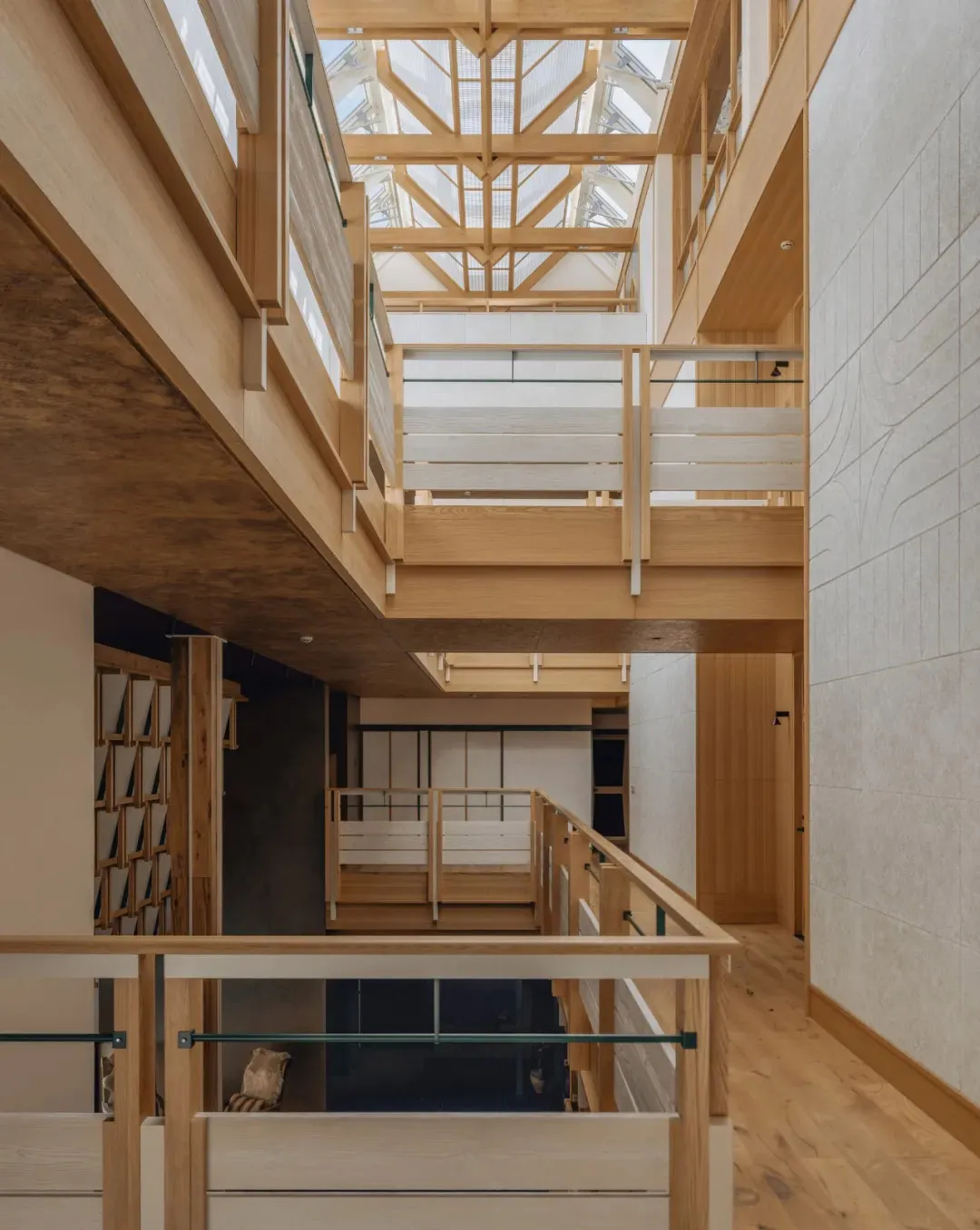 Open-plan living and dining space with wooden floors, a glass railing, and a dining table and chairs, well-lit and inviting