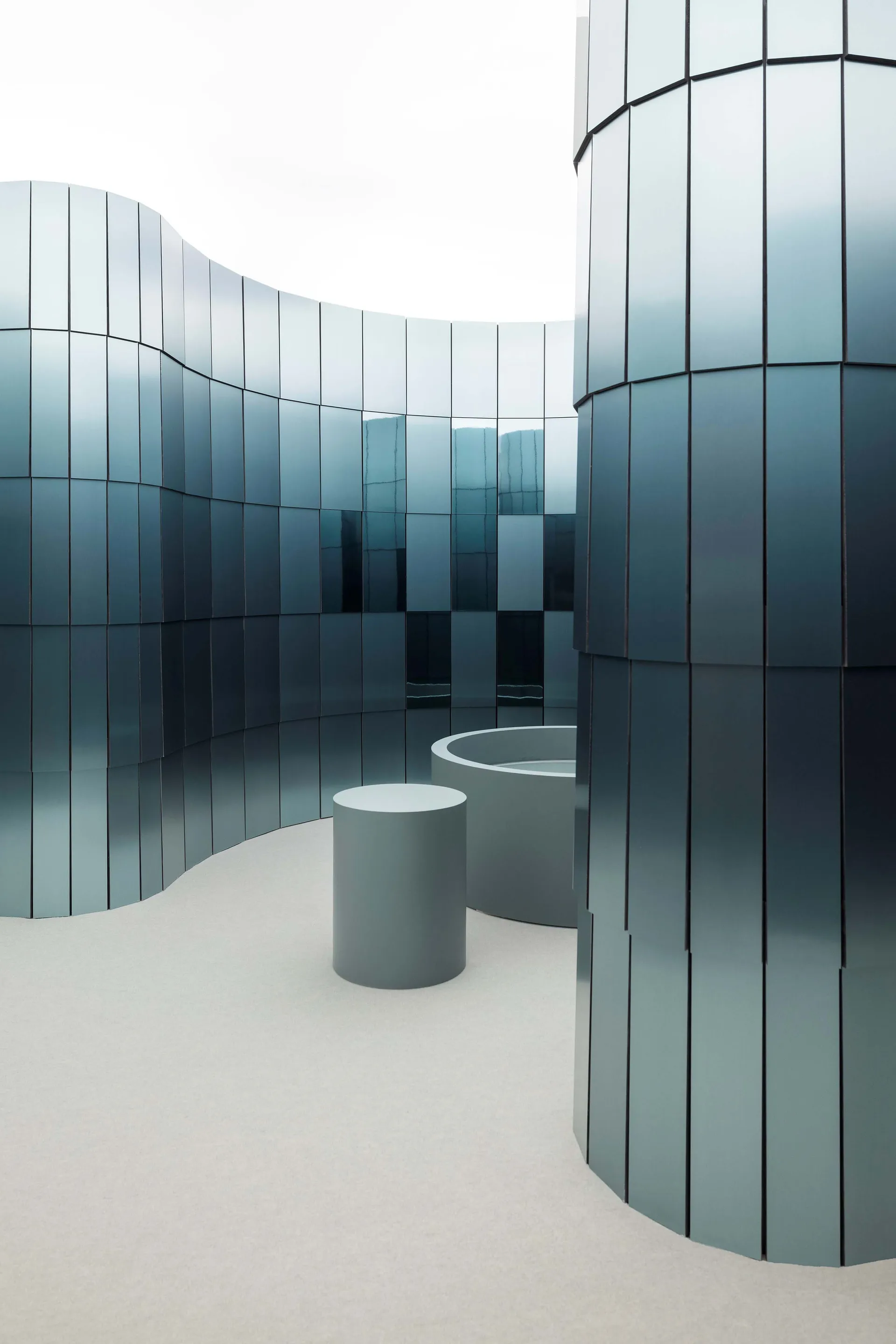 Modern minimalist room with a curved wall, a circular table, and glass walls, surrounded by chairs in a blue color scheme