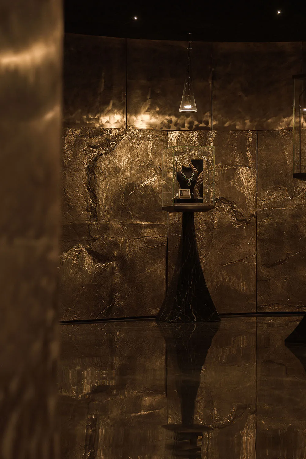 A dimly lit room with a marble floor and gold wall, featuring a black table with a trophy and a gold statue, creating a luxurious and elegant atmosphere
