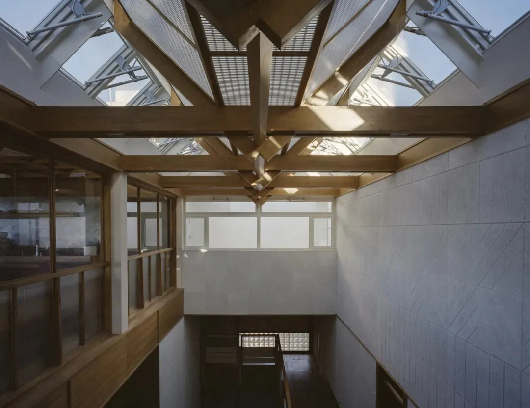 A large, open room with a wooden floor, skylight, and natural light, featuring a staircase and seating areas