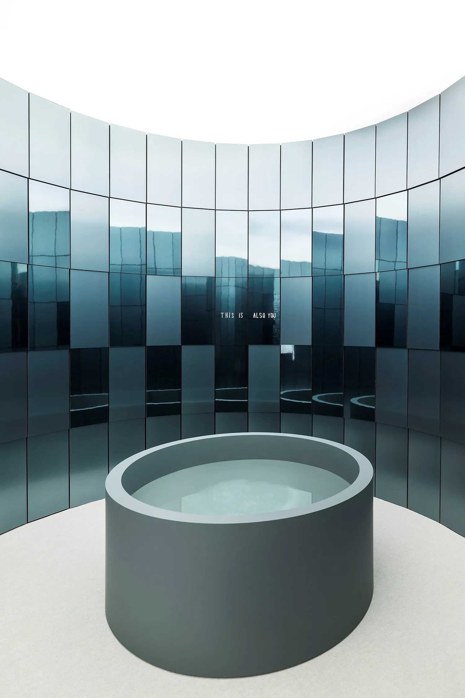 A modern room with a circular pool surrounded by glass walls, creating an open and airy atmosphere