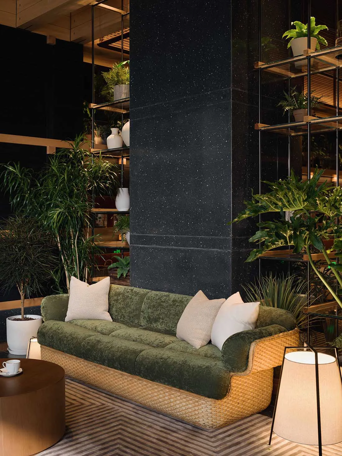 Cozy living room with a green sofa, coffee table, and several potted plants, creating a natural and inviting atmosphere