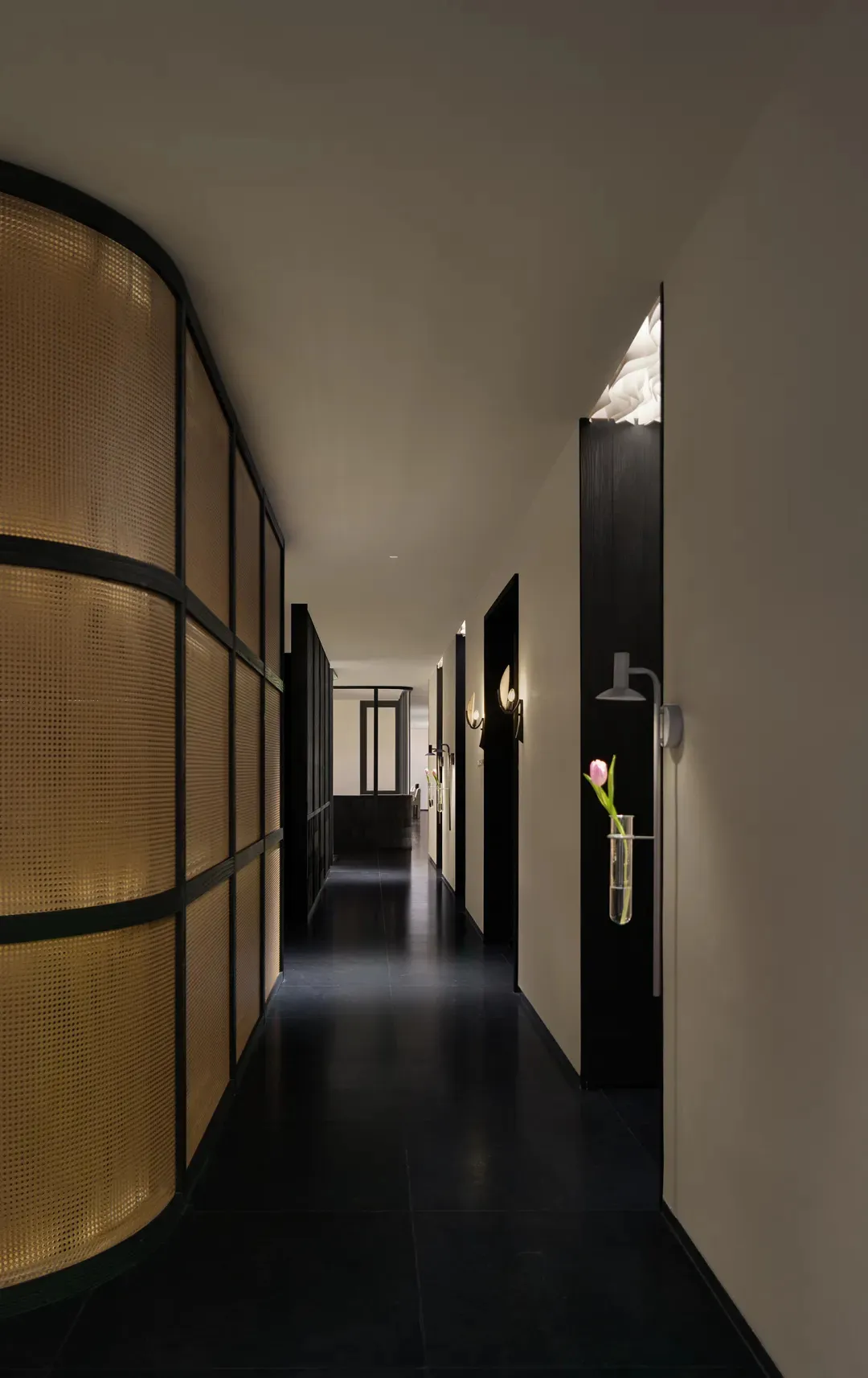 A dimly lit hallway with a black and white color scheme, wooden walls, and two doors