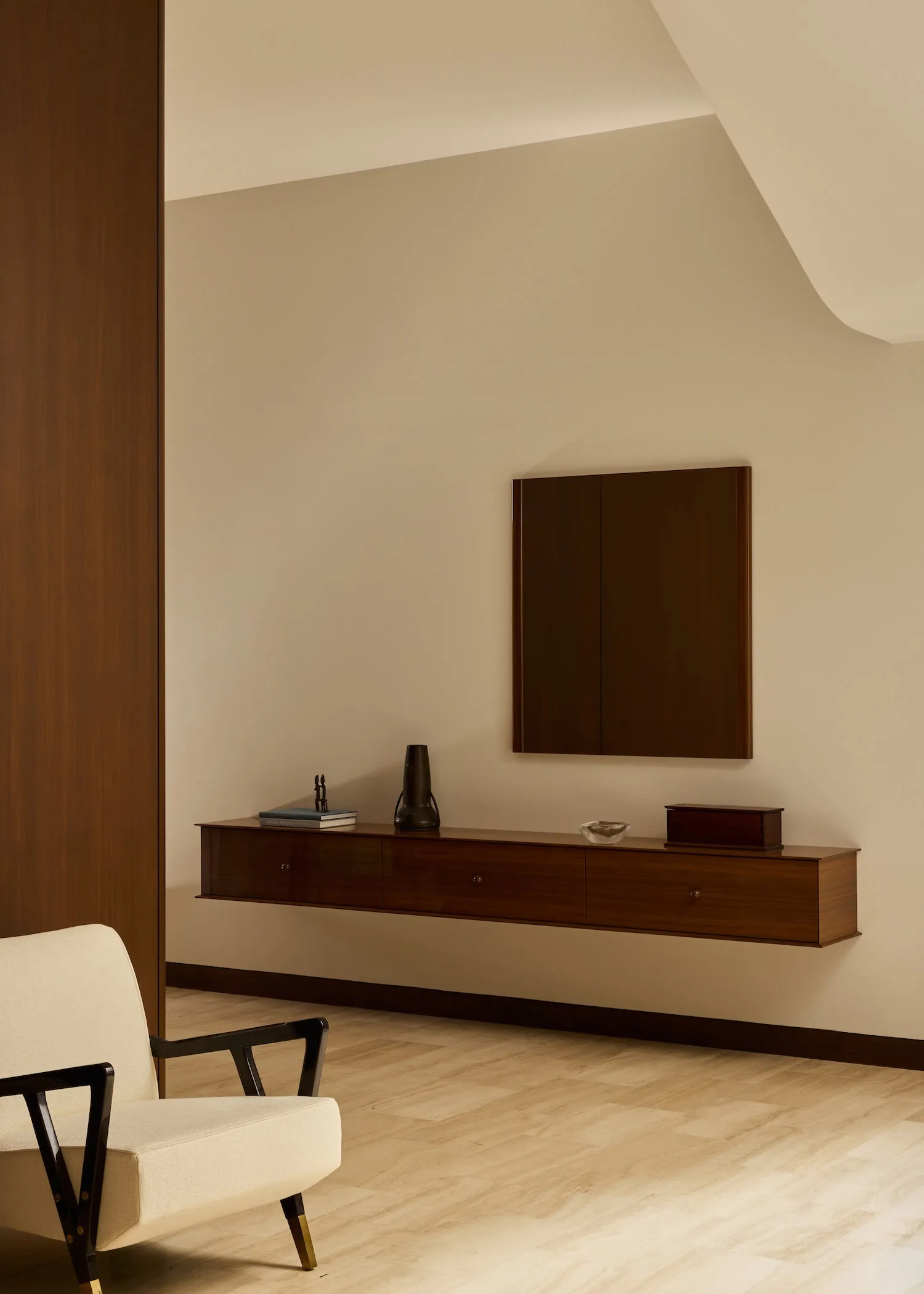 A modern living room with a wooden floor, a chair, a couch, and a dresser, well-lit and inviting