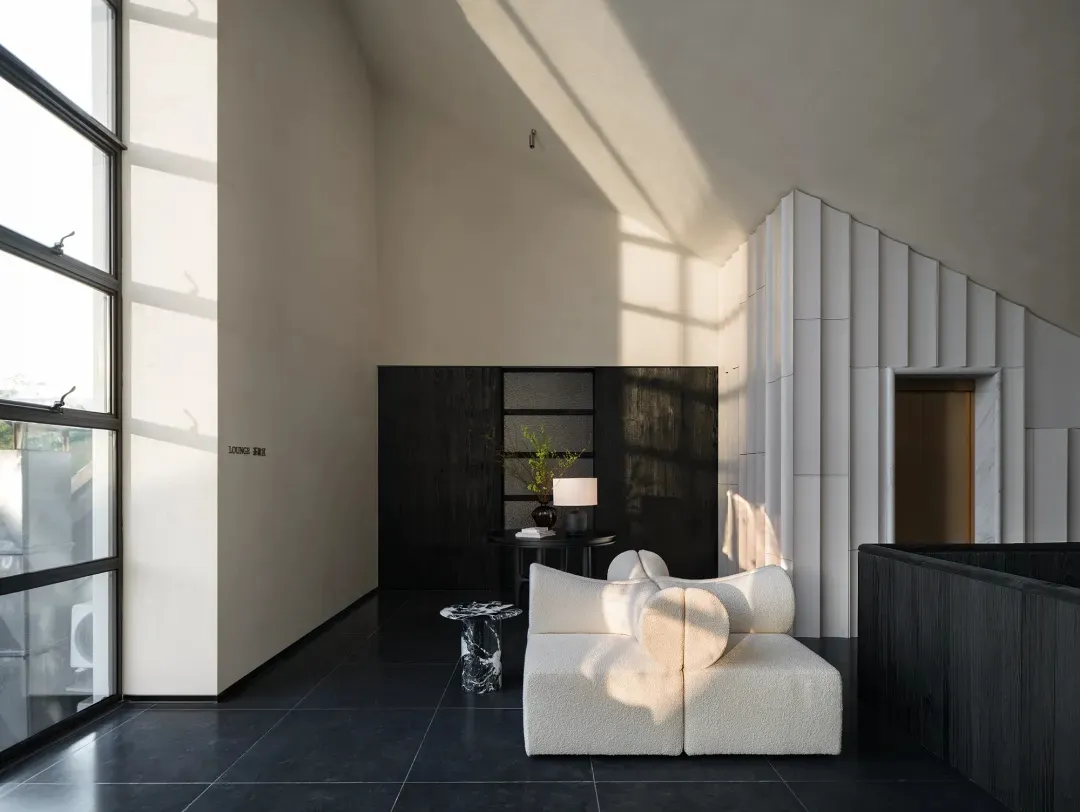 A well-lit living room with a modern design, featuring a white couch, chair, and dining table, with natural light coming in through the windows