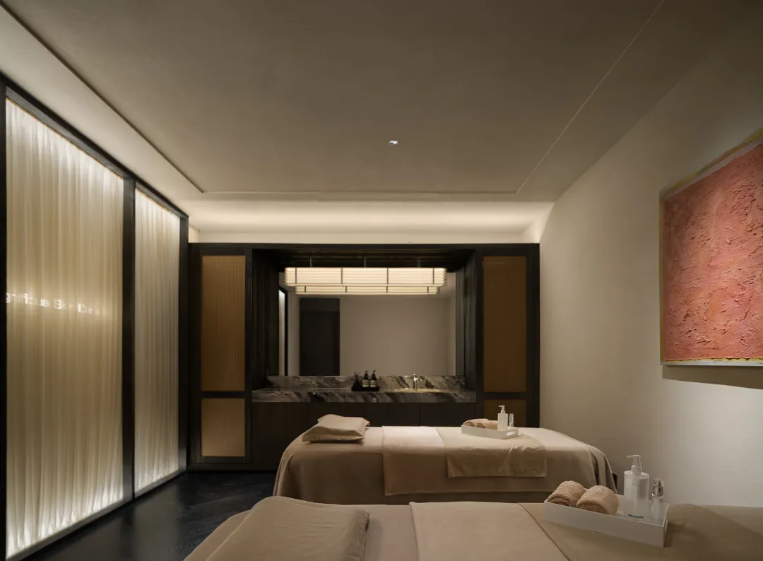 Cozy hotel room with a brown color scheme, featuring a large bed, counter, and sink, with toiletries and amenities scattered around